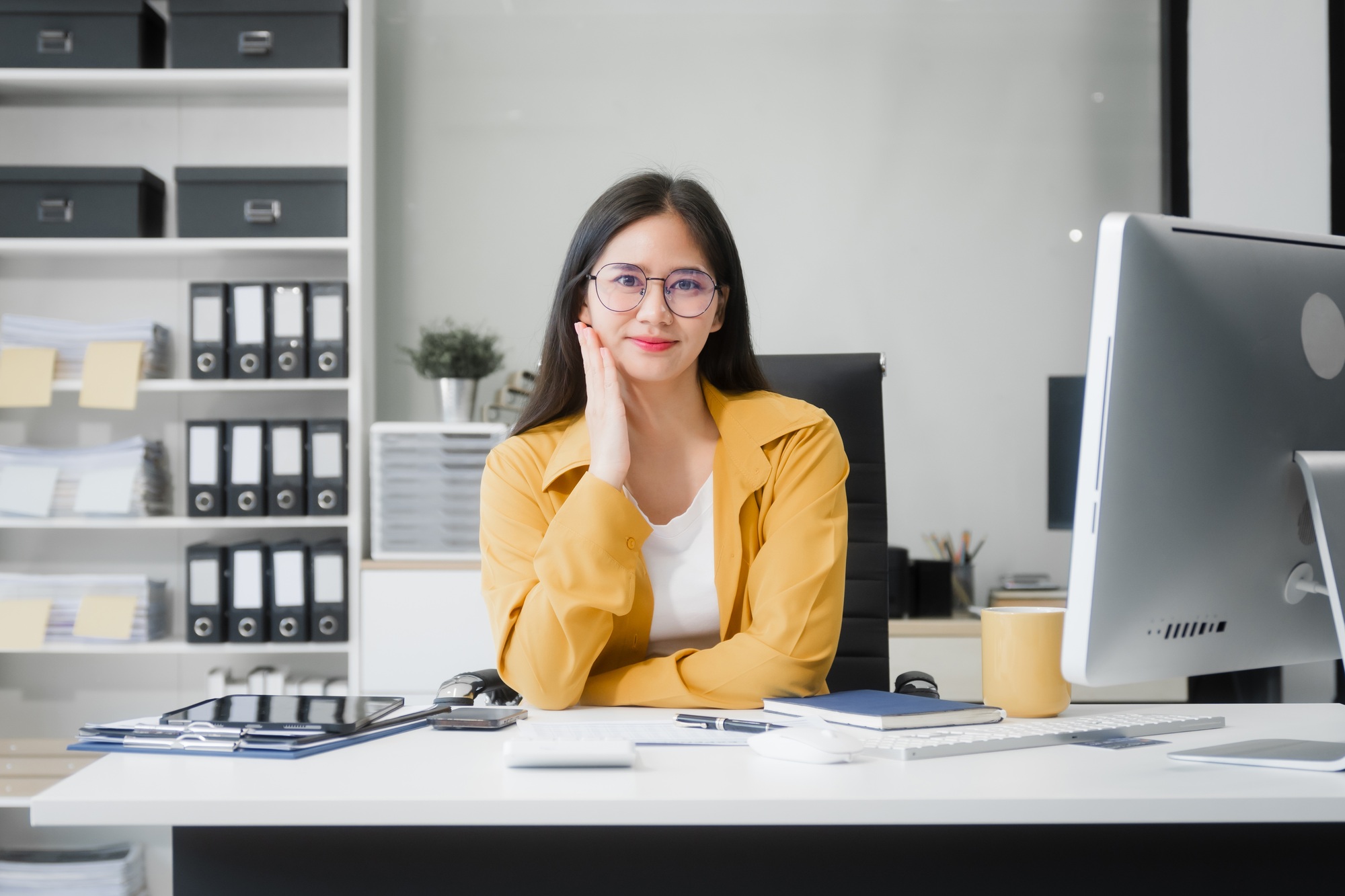 Young Asian woman at desk, managing HR, legal consulting, and compliance amidst files