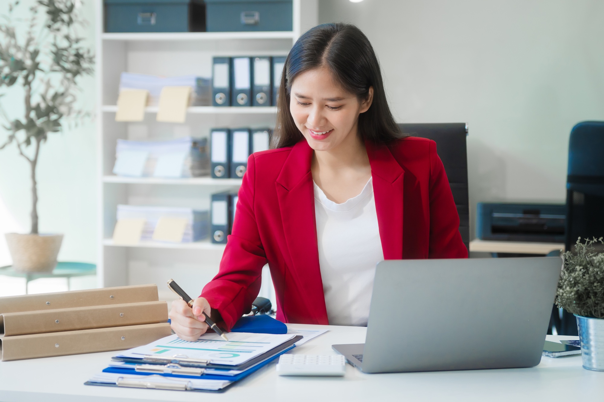 Young Asian woman at desk, strategizing marketing funnels and SEO in a bright office setting.