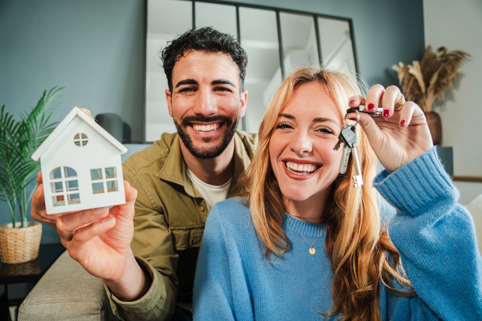 Young couple celebrating a beginning at their new home holding the key of the house. Real estate