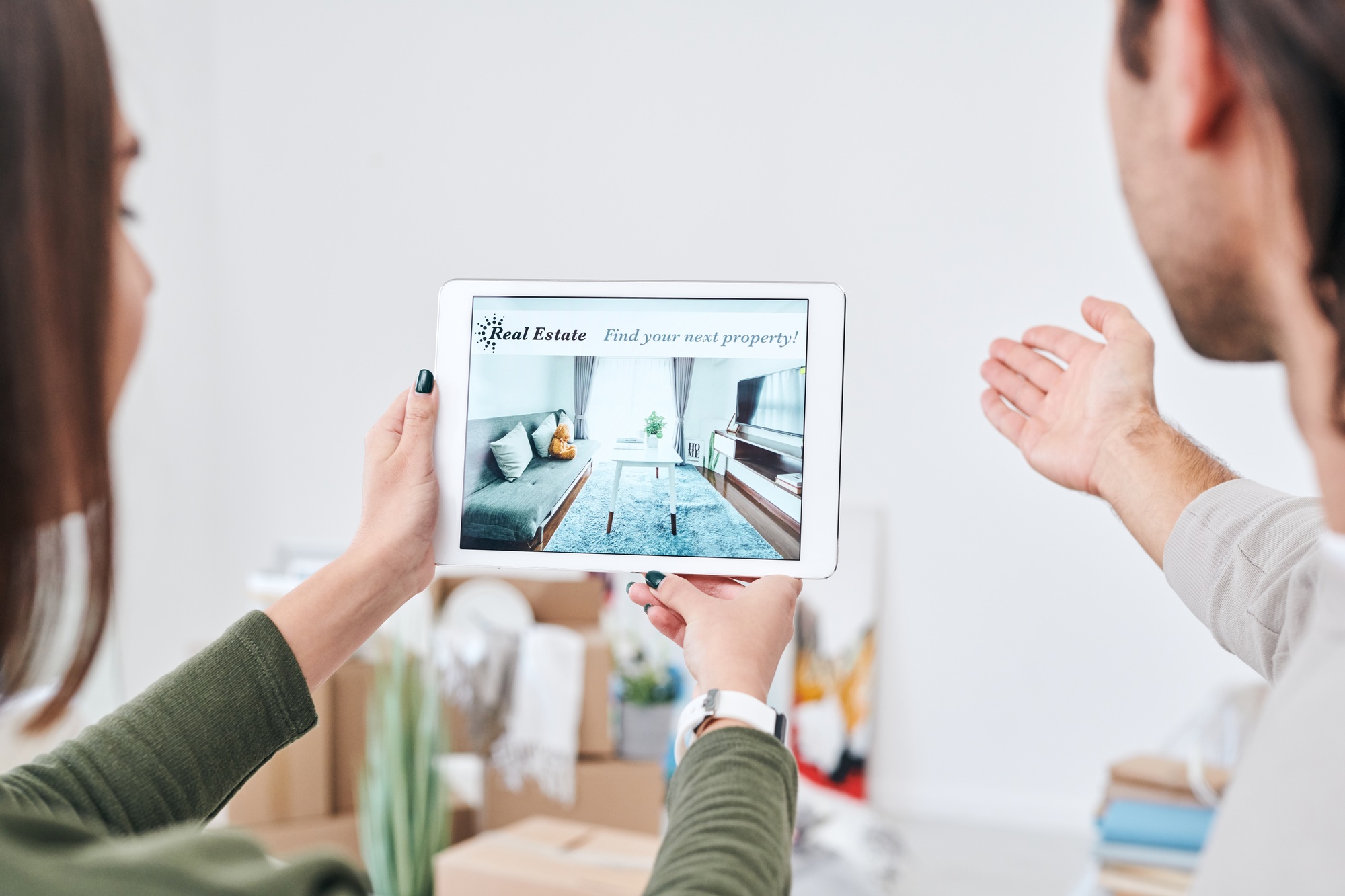 Young woman holding touchpad with advertisement of new real estate on screen