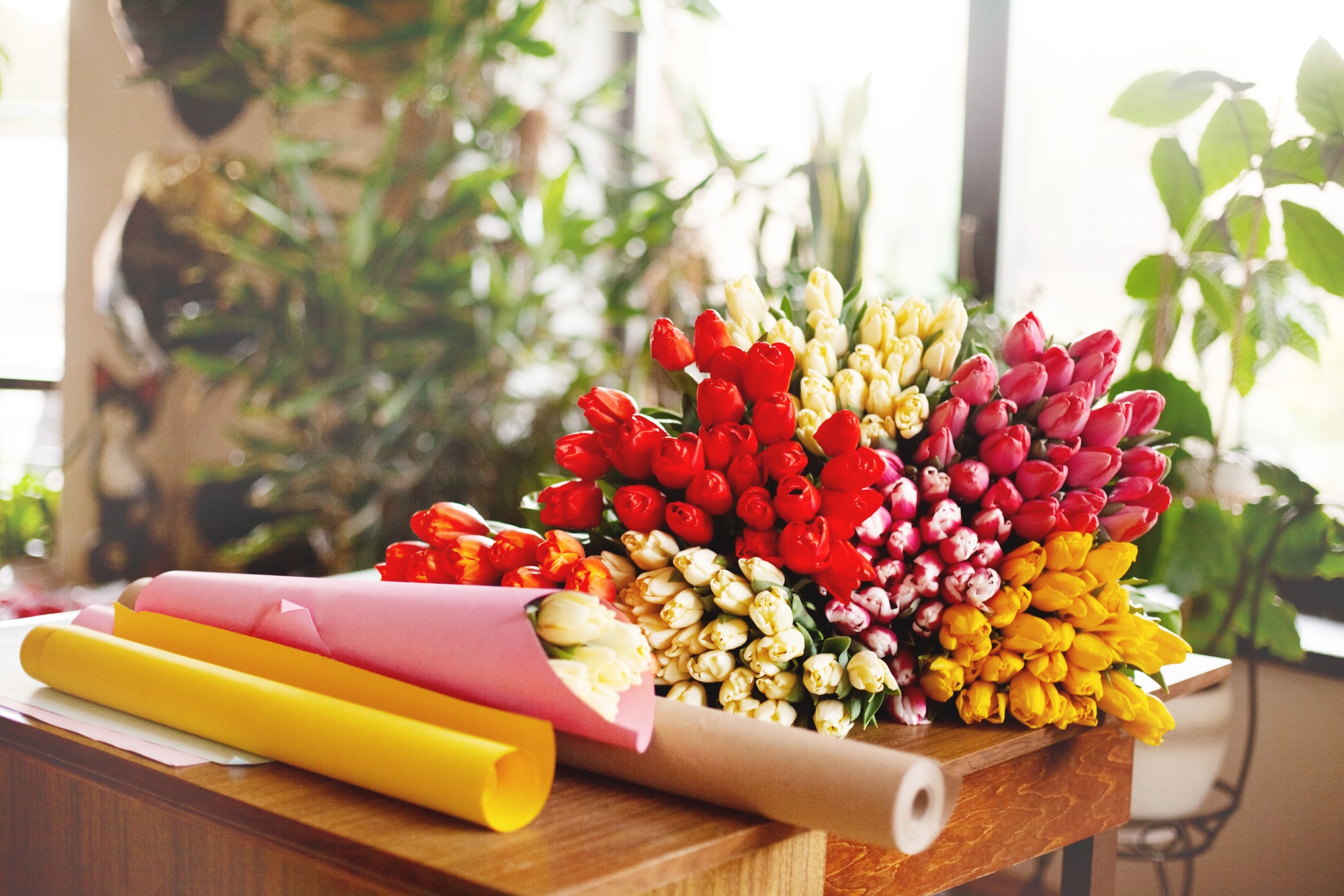 A bouquet of fresh spring tulips on a wooden table, next to the craft paper. Valentine's Day