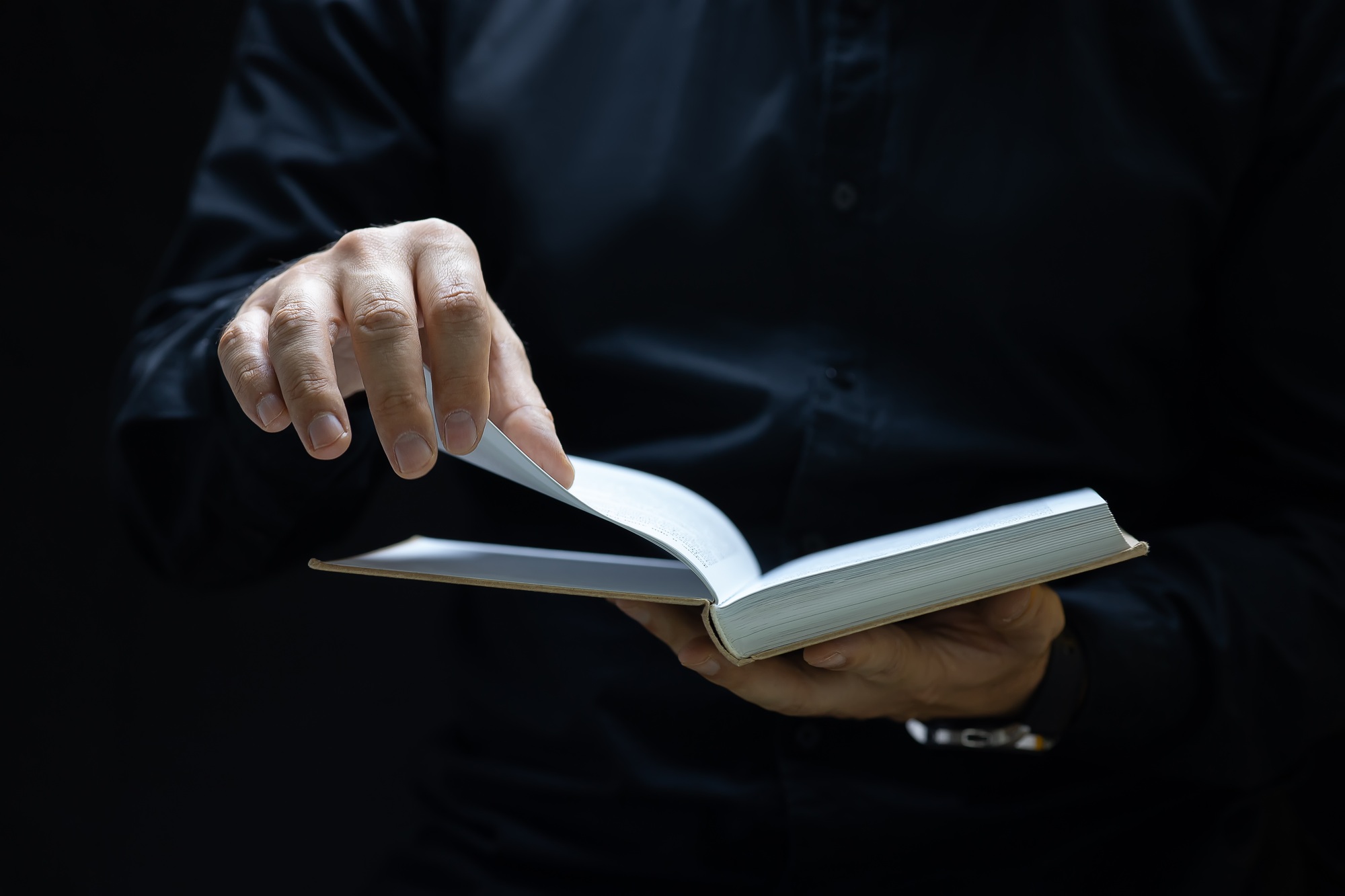 a male businessman holds a book about business and promotion tries to turn the page on the next