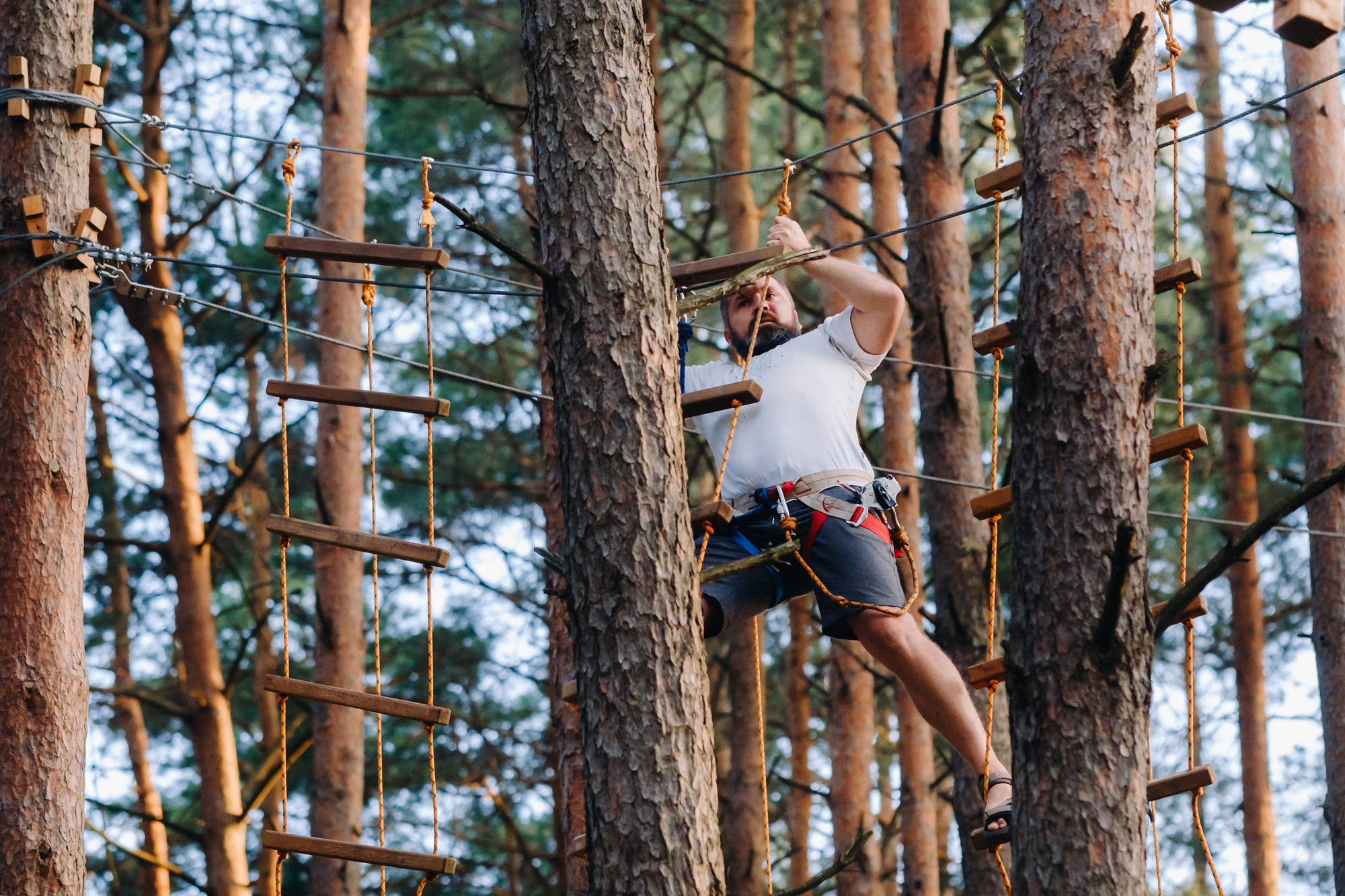 A man overcomes an obstacle in a rope town. A man in a forest rope park