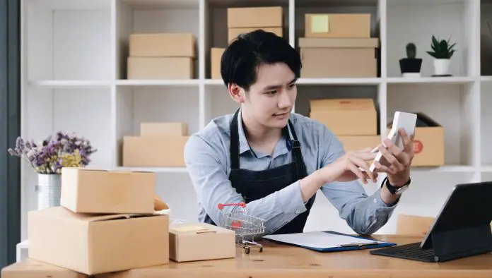 A portrait of Asian man, e-commerce employee sitting in the office full of packages on the table