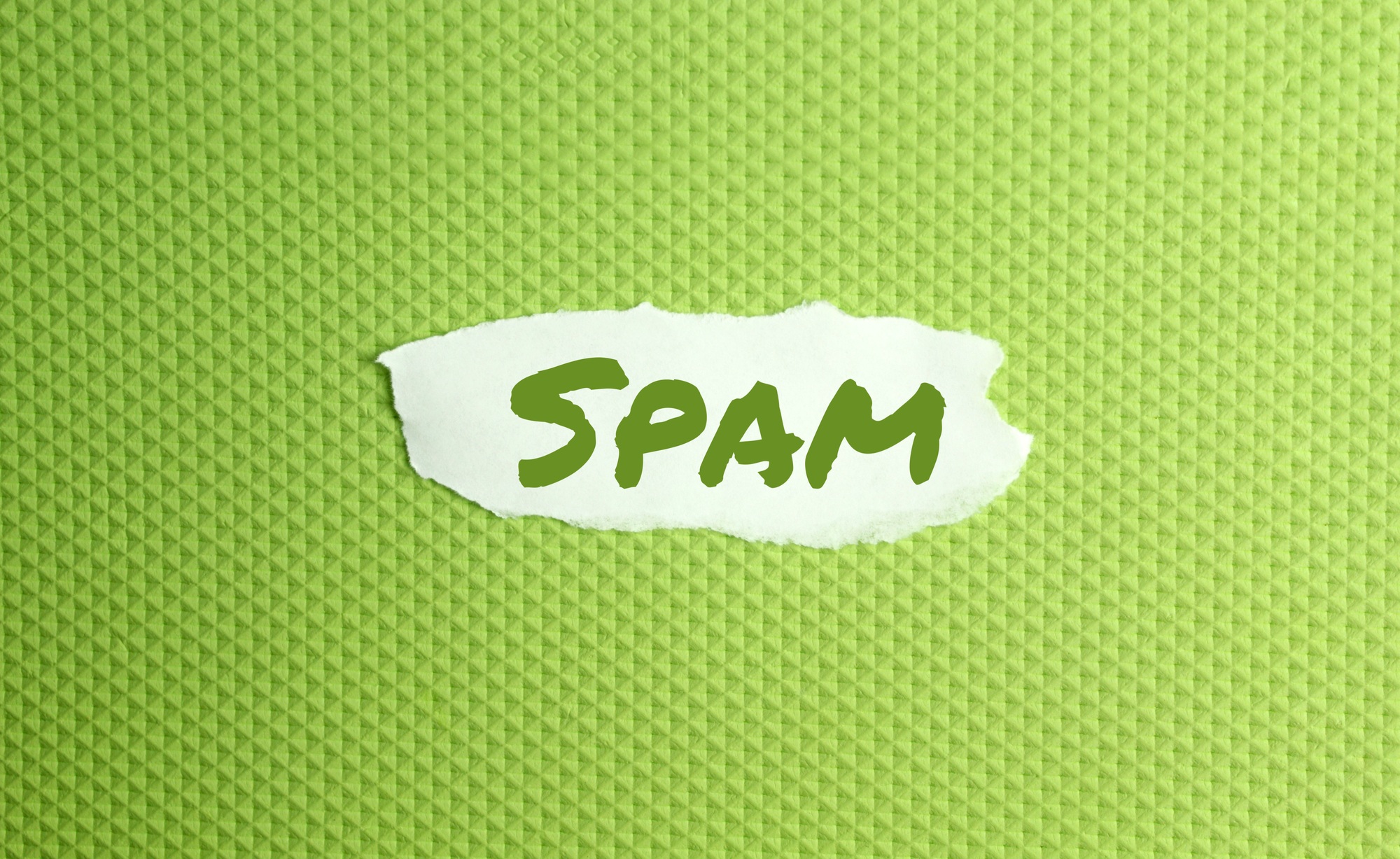 a torn paper written with inscription spam on a green background