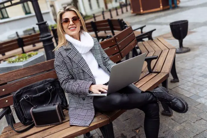 adult successful woman entrepreneur working on laptops in city square online