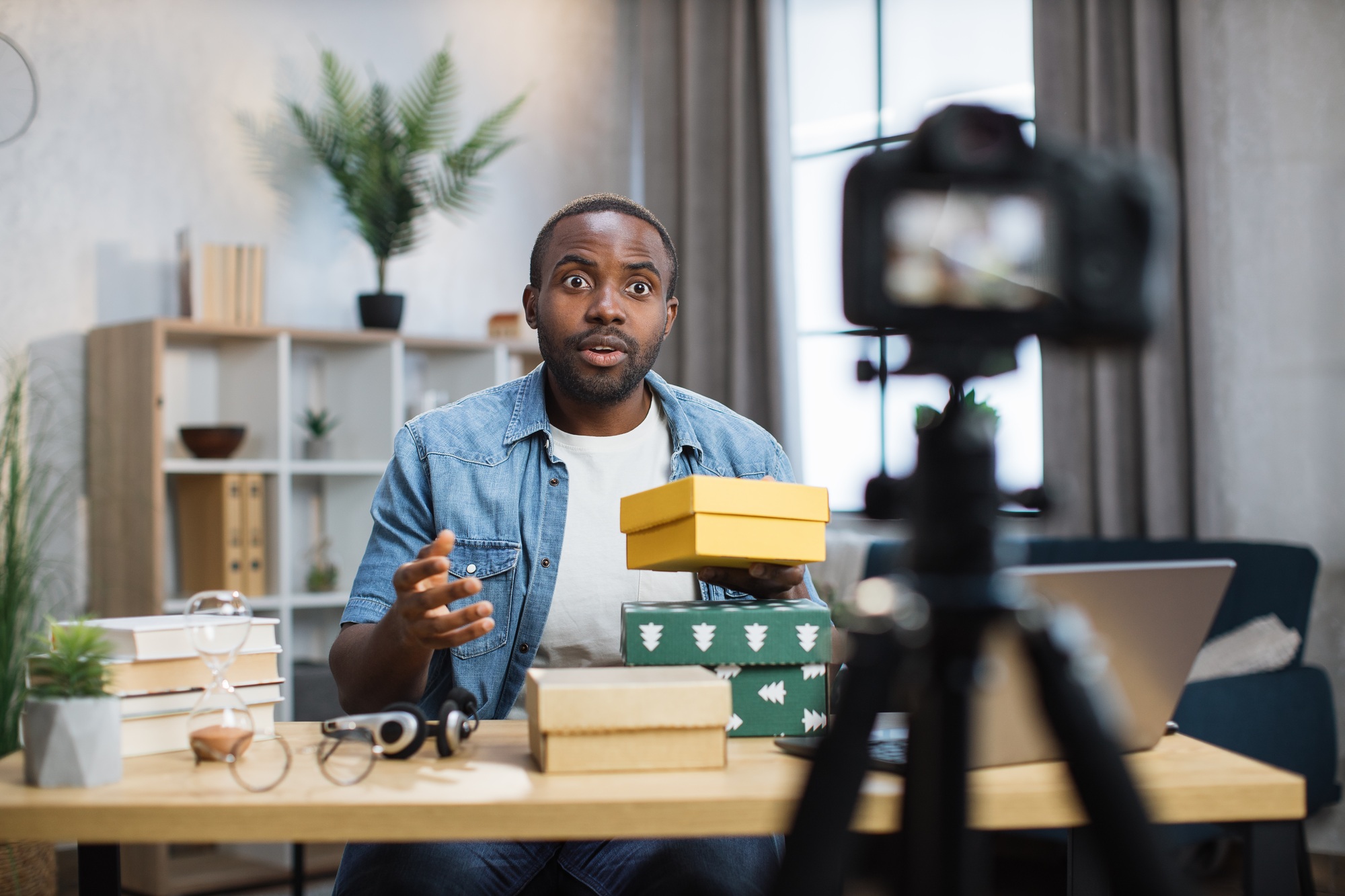 African blogger recording video while unpacking gift boxes