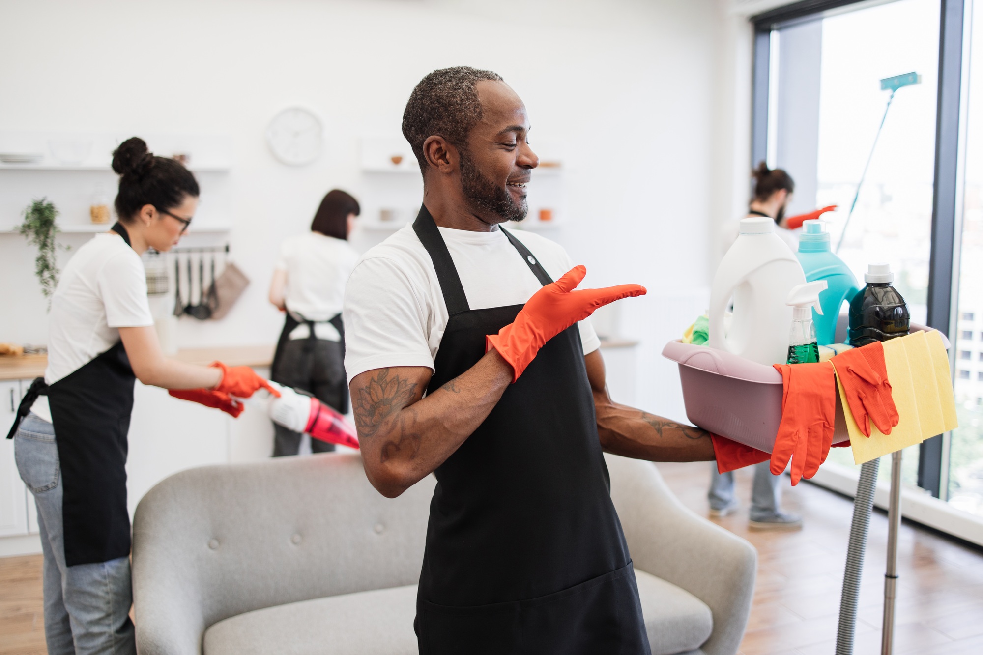 American man professional cleaning worker pointing on bucket with detergents.