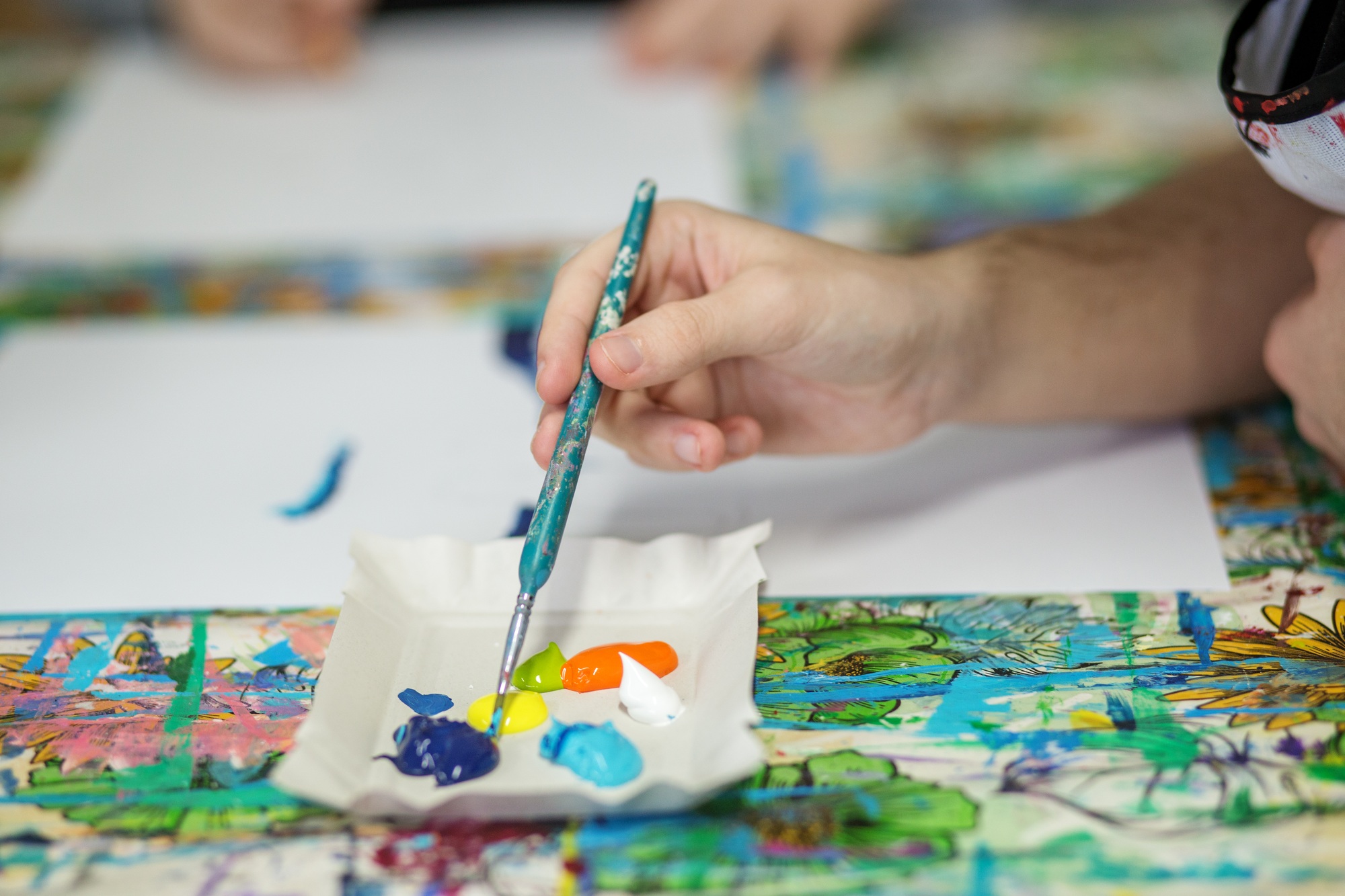 Artist's Hand Mixing Acrylic Paints on Palette.