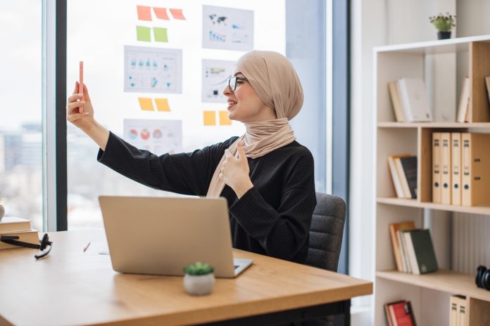 Assistant joining online meeting via phone at office desk