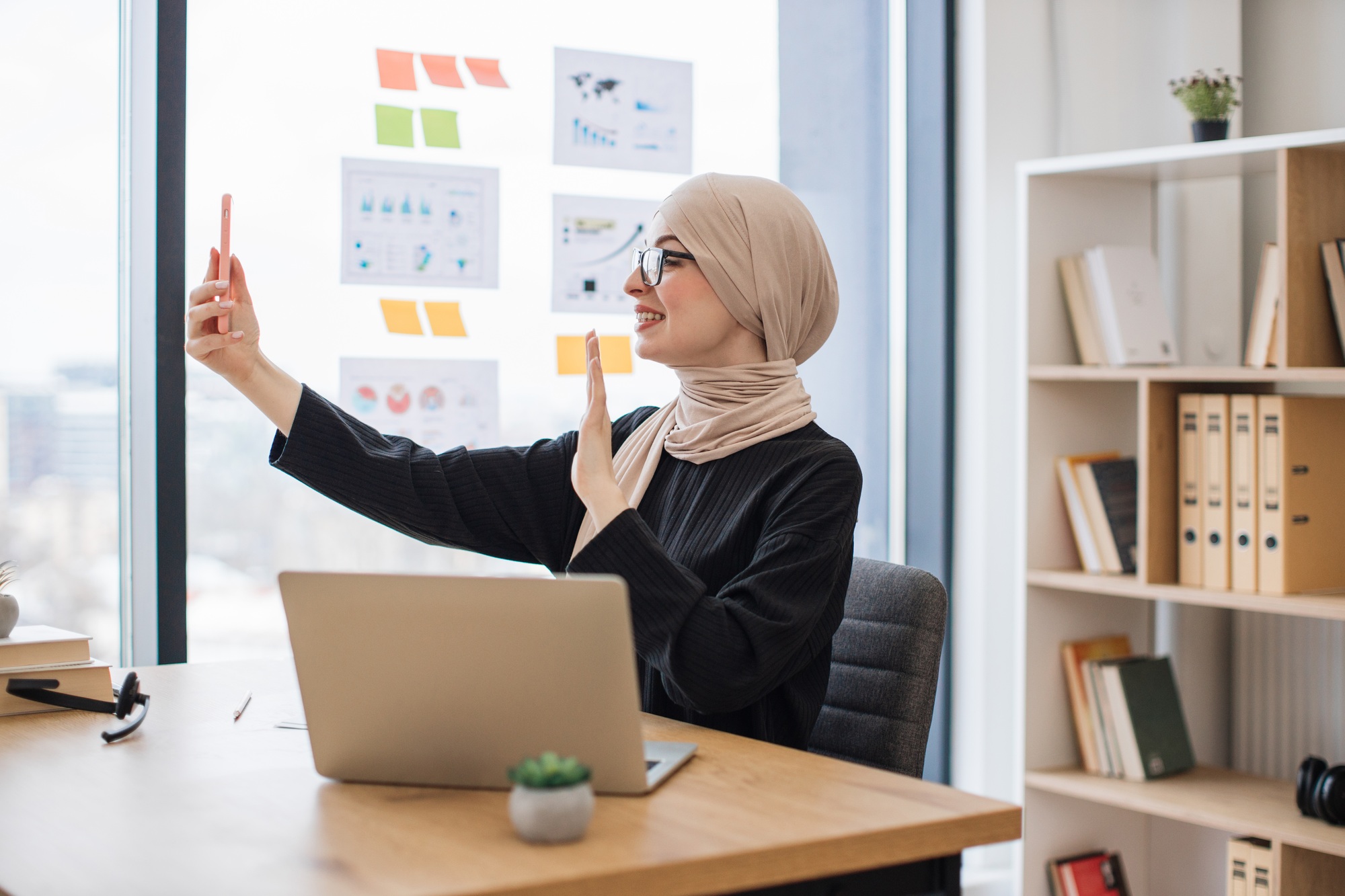 Assistant joining online meeting via phone at office desk