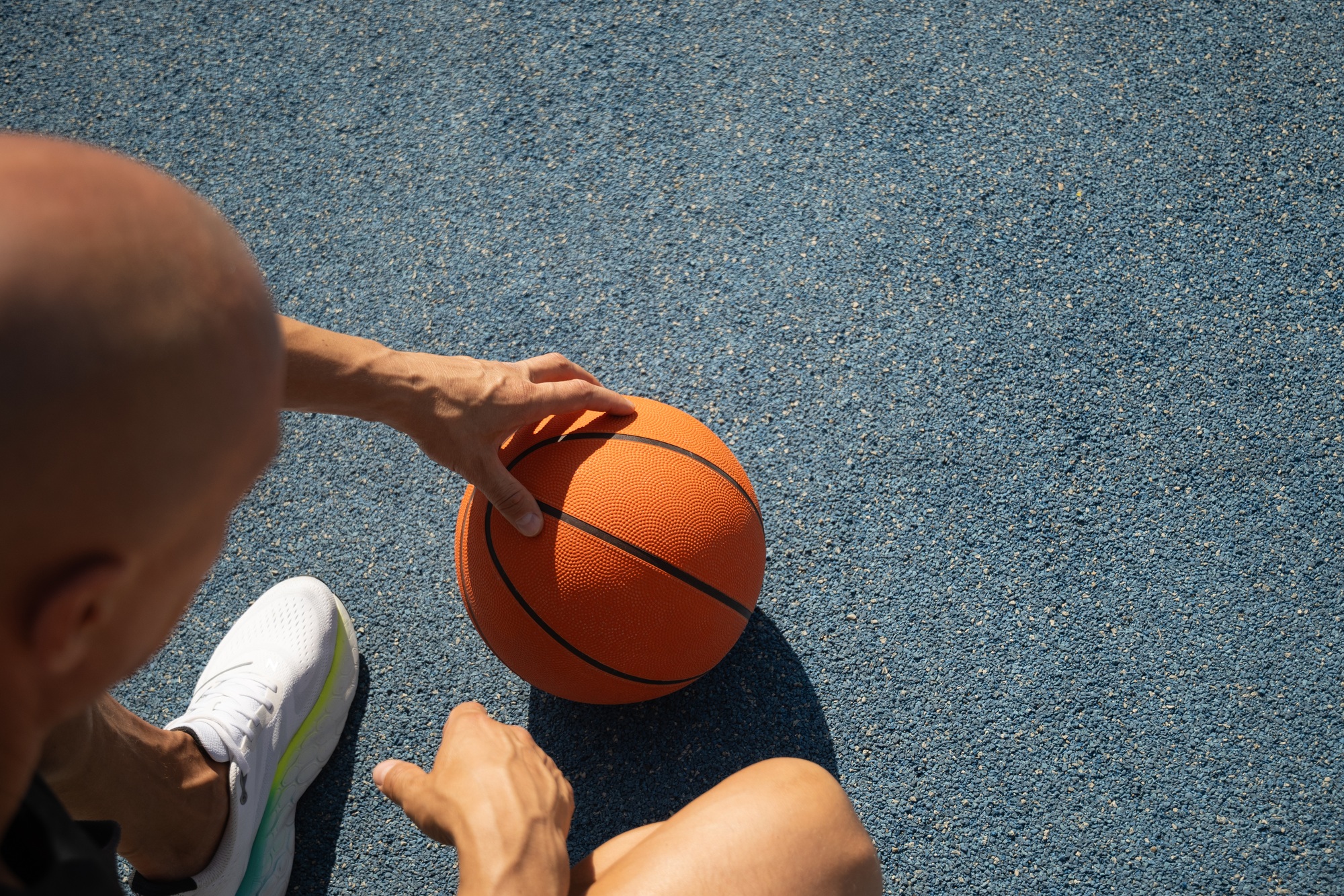 Basketball player relaxing and sitting after game. Outdoor training.