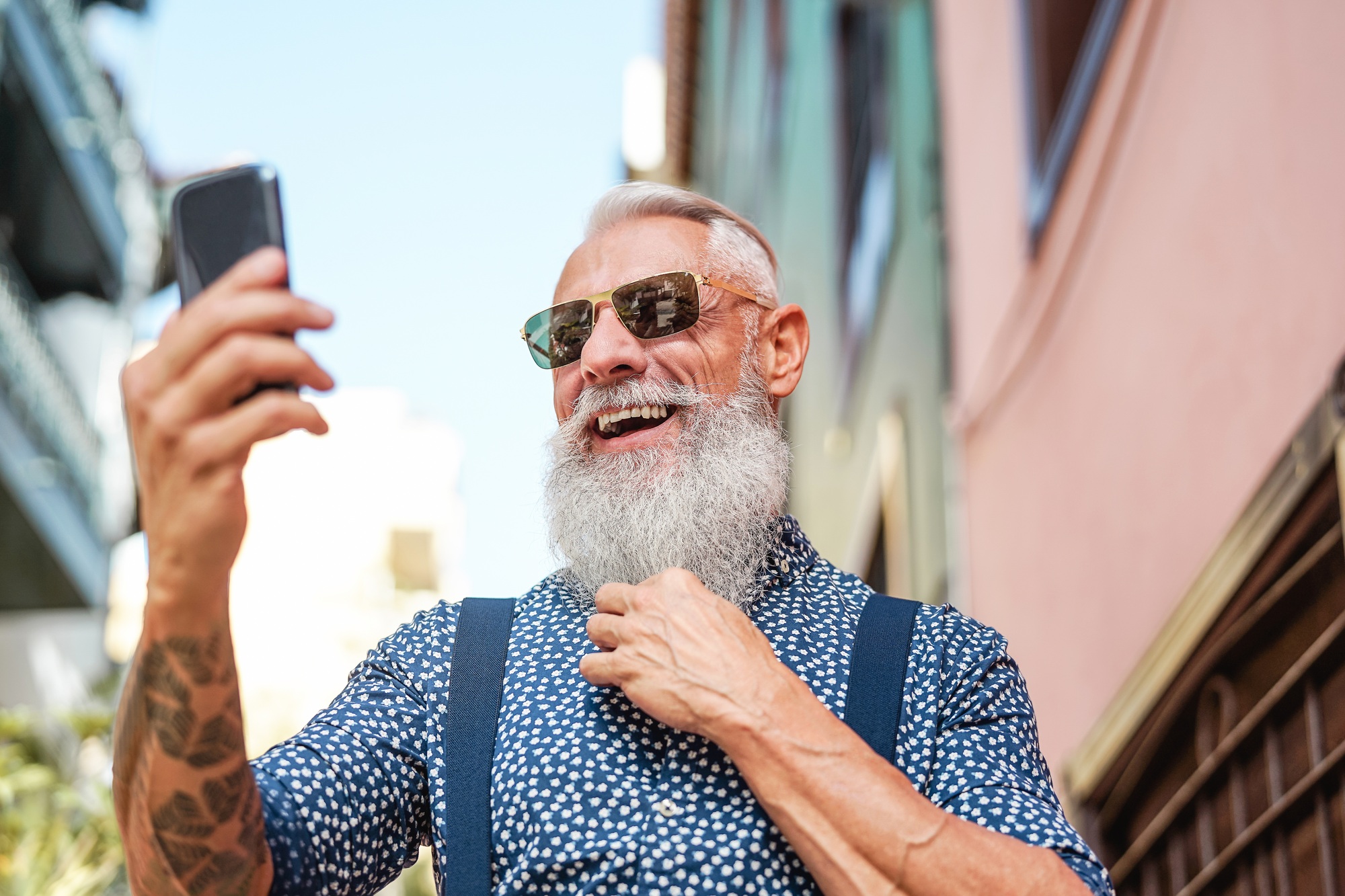 Bearded senior using mobile phone outdoor