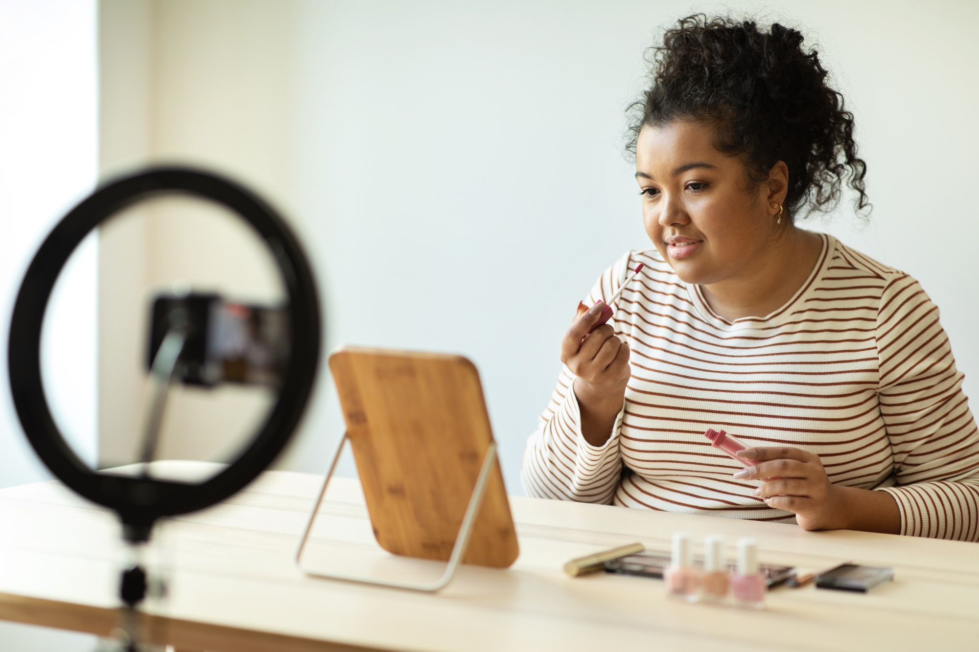 Beautiful makeup artist applying lip gloss and streaming