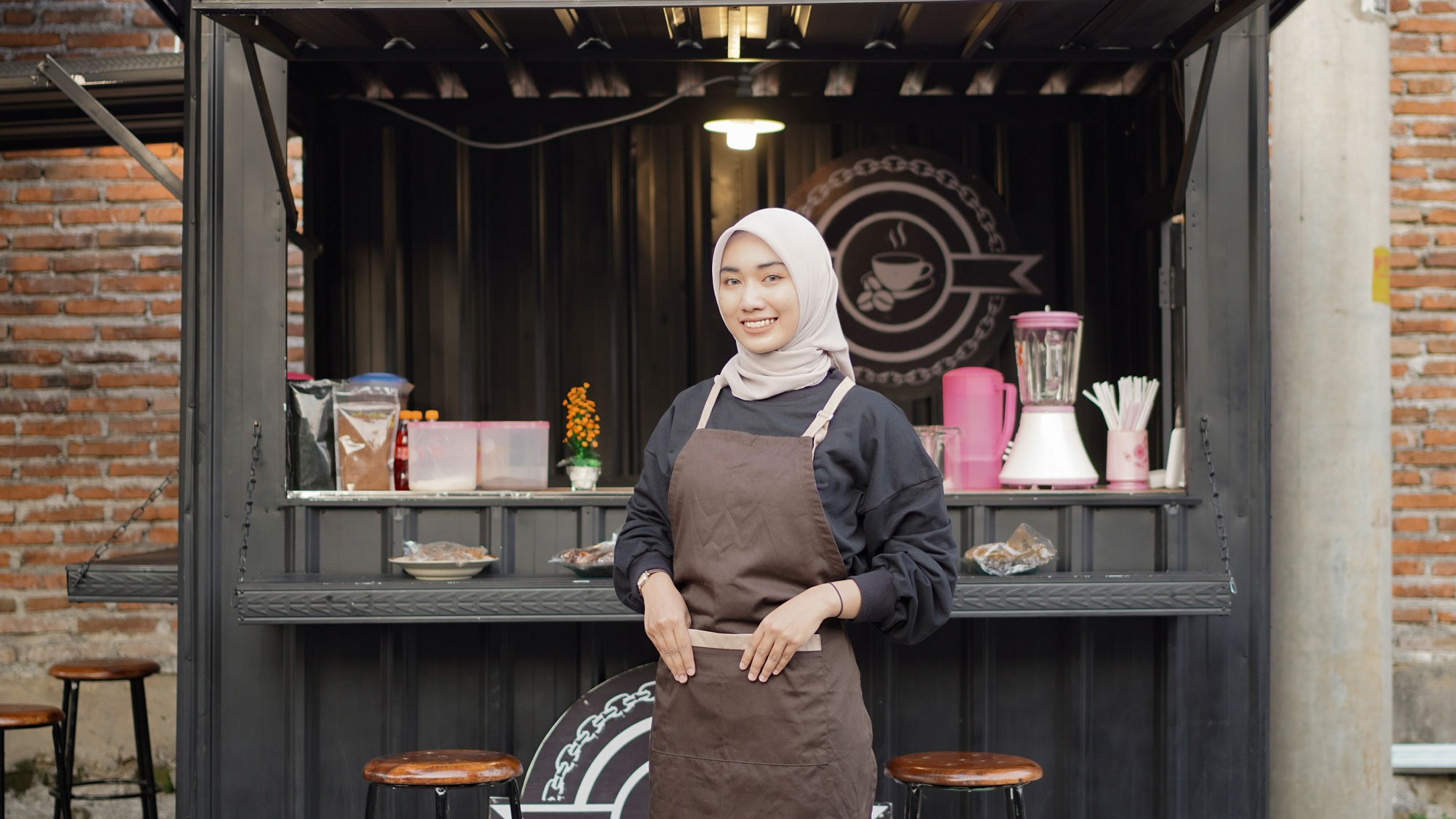 Beautiful smiling barista ready to open cafe booth container