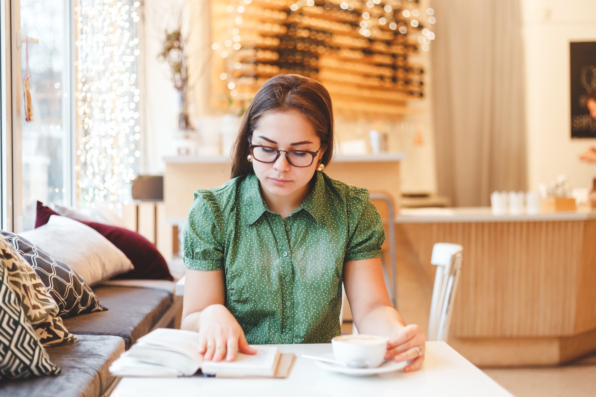 Beautiful young woman relaxing and reading a book in  coffee shop