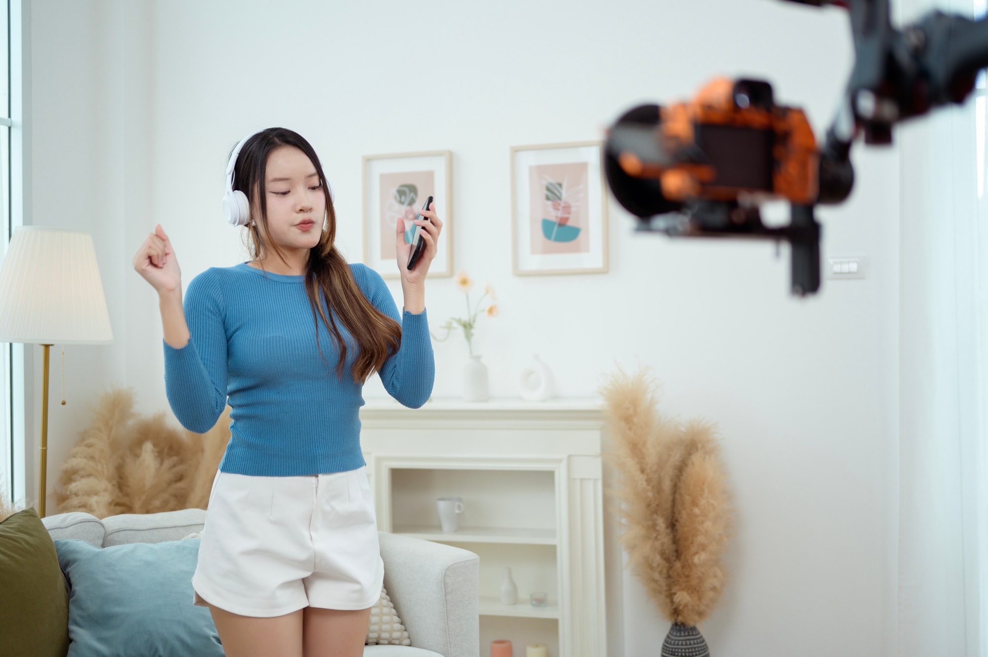 Behind the scenes videographer recording a young Asian woman listening music