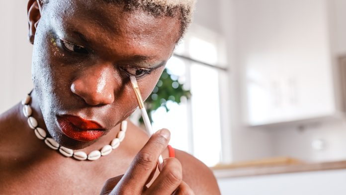 Black man applying makeup at home