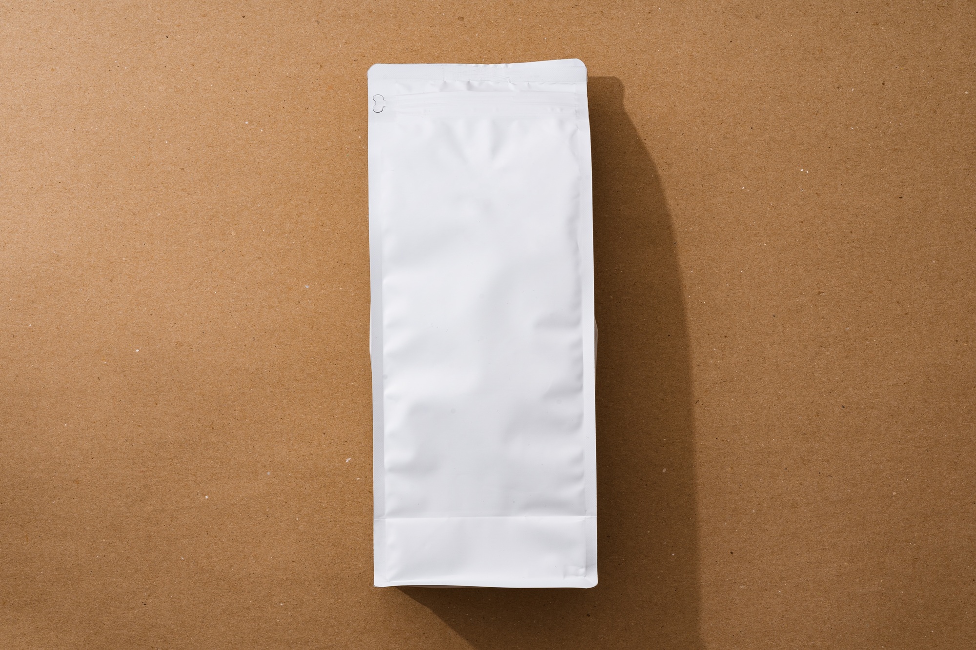 Blank package with coffee beans for your design on beige background