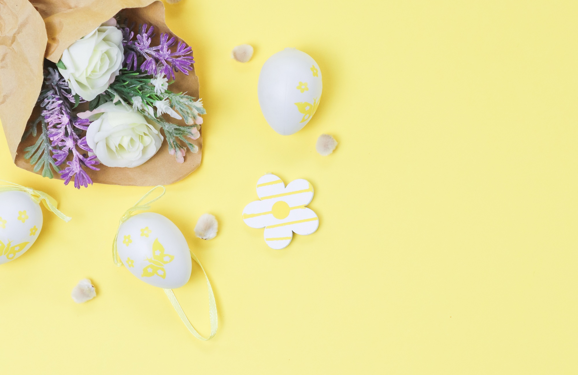 Bouquet of artificial spring flowers in craft paper with willow buds and decorative Easter eggs