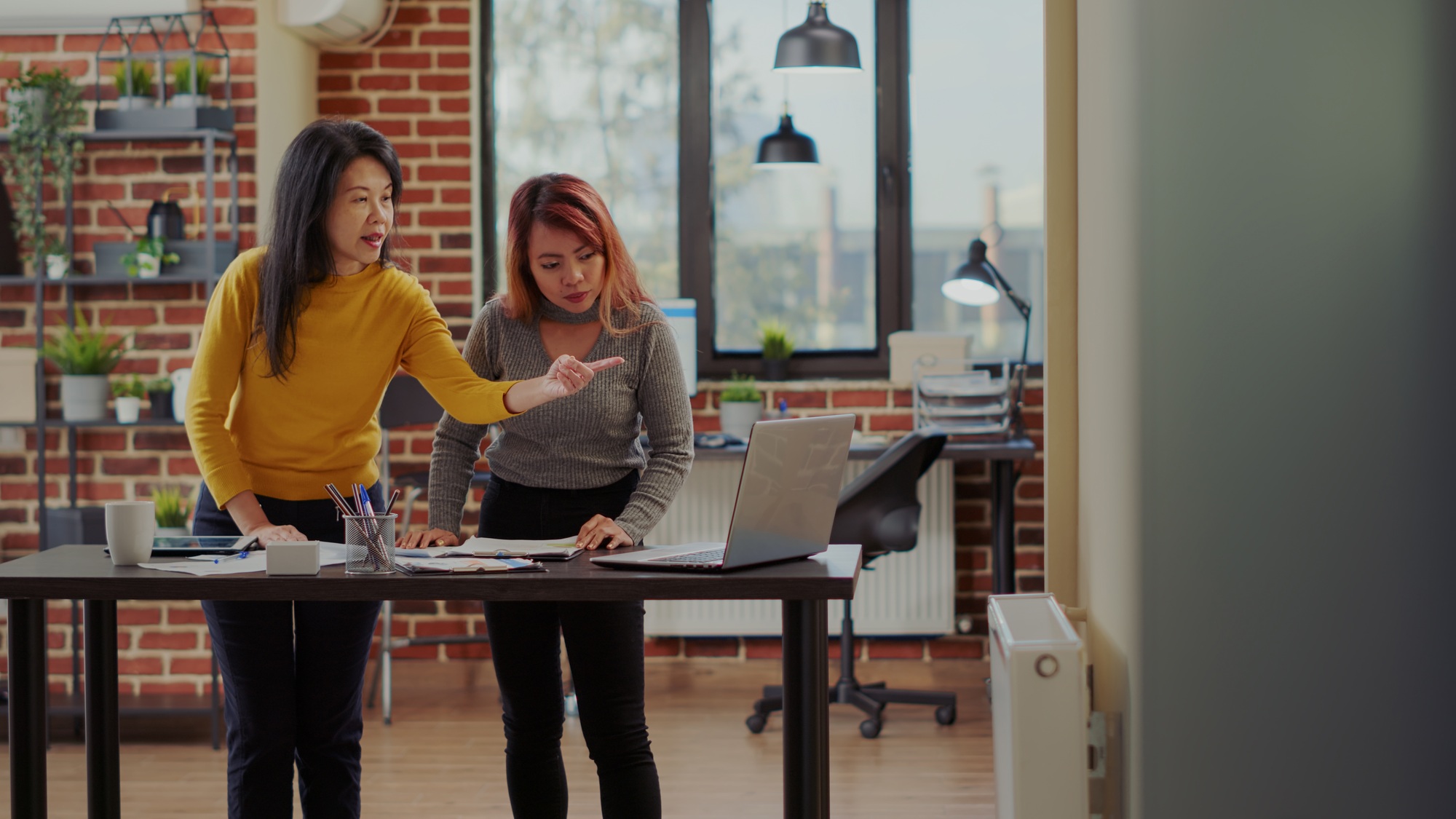 Business women pointing at laptop to brainstorm ideas