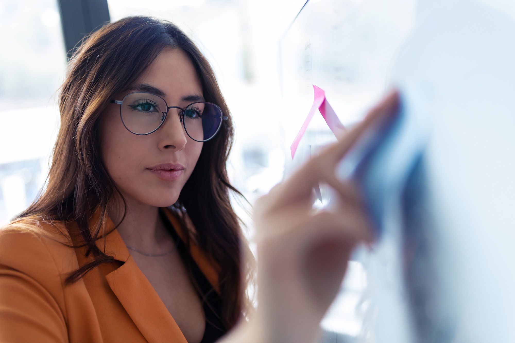 Business young woman working on white board with post it stickers in the office.