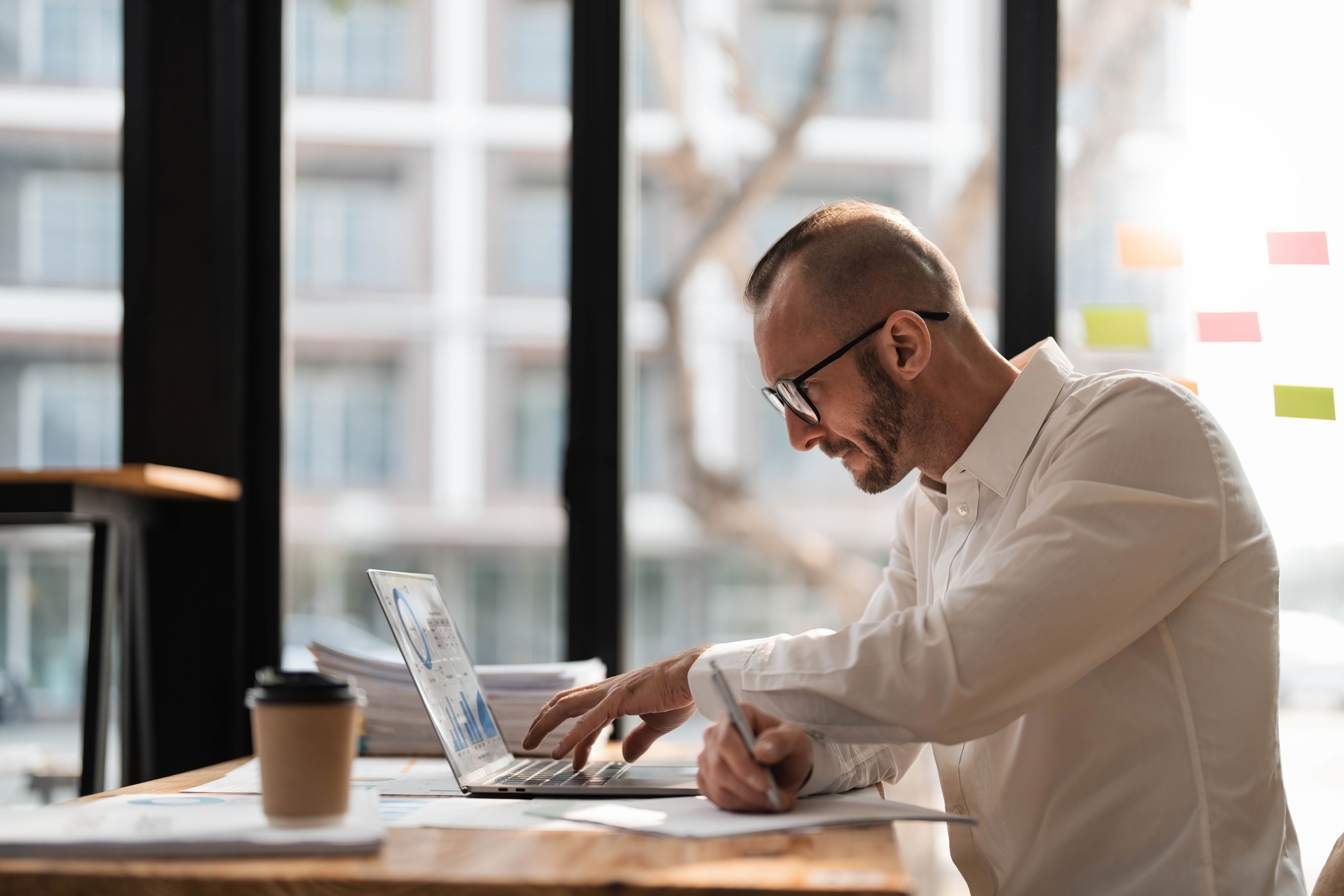 Businessman using laptop computer in office. Happy middle aged man, entrepreneur, small business