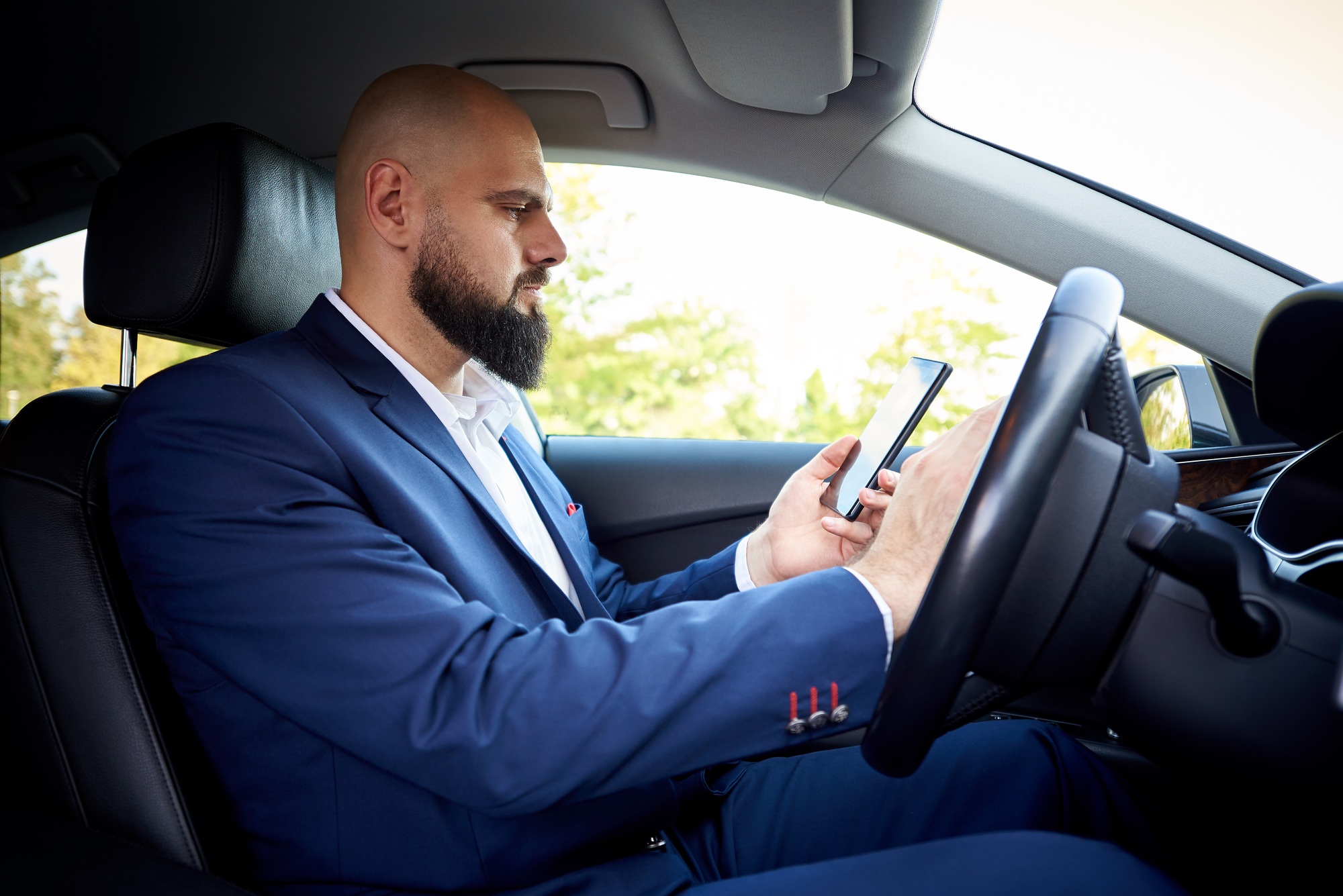 Businessman with smartphone in auto