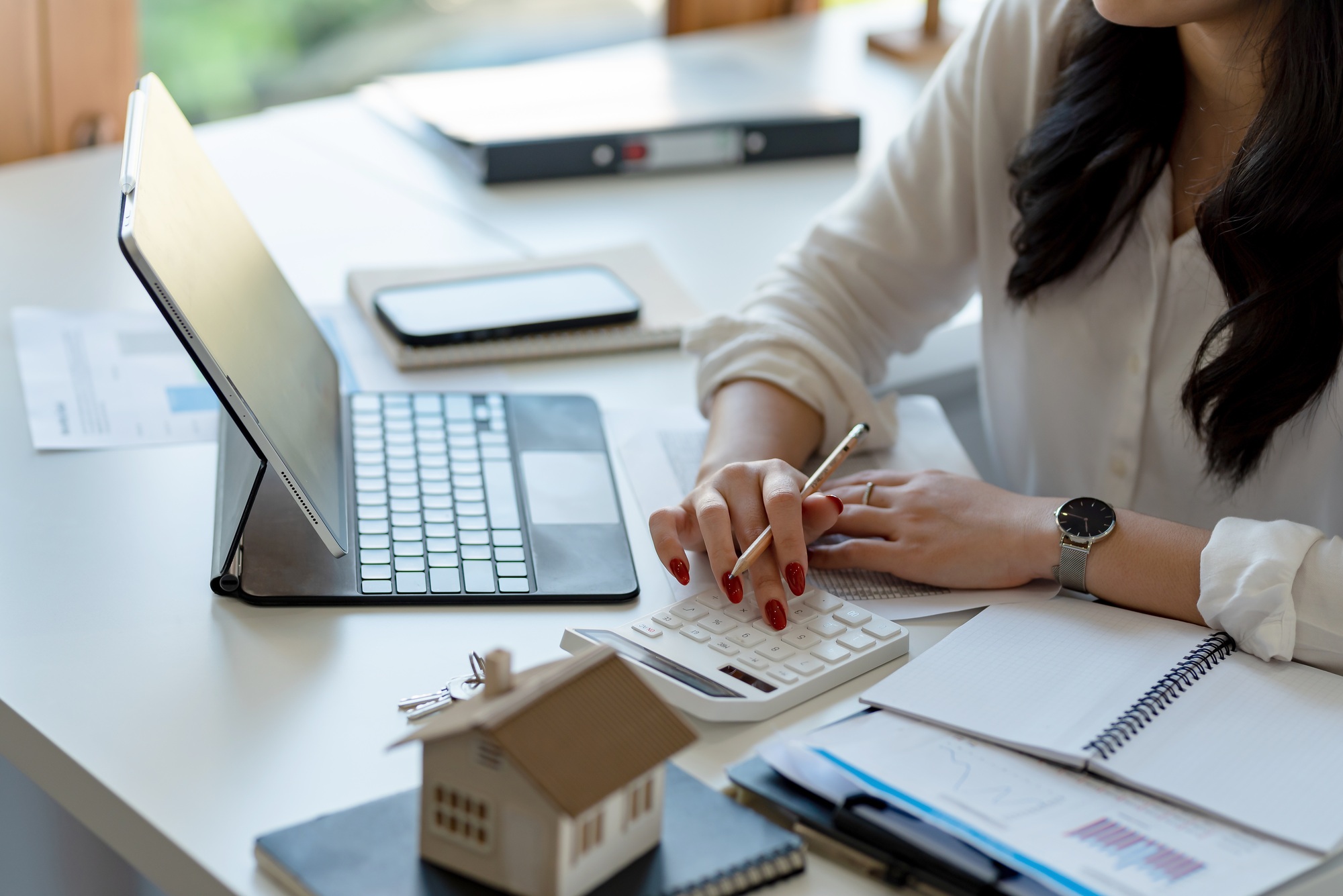 Businesswoman doing finances and calculate about cost to real estate investment in the office.