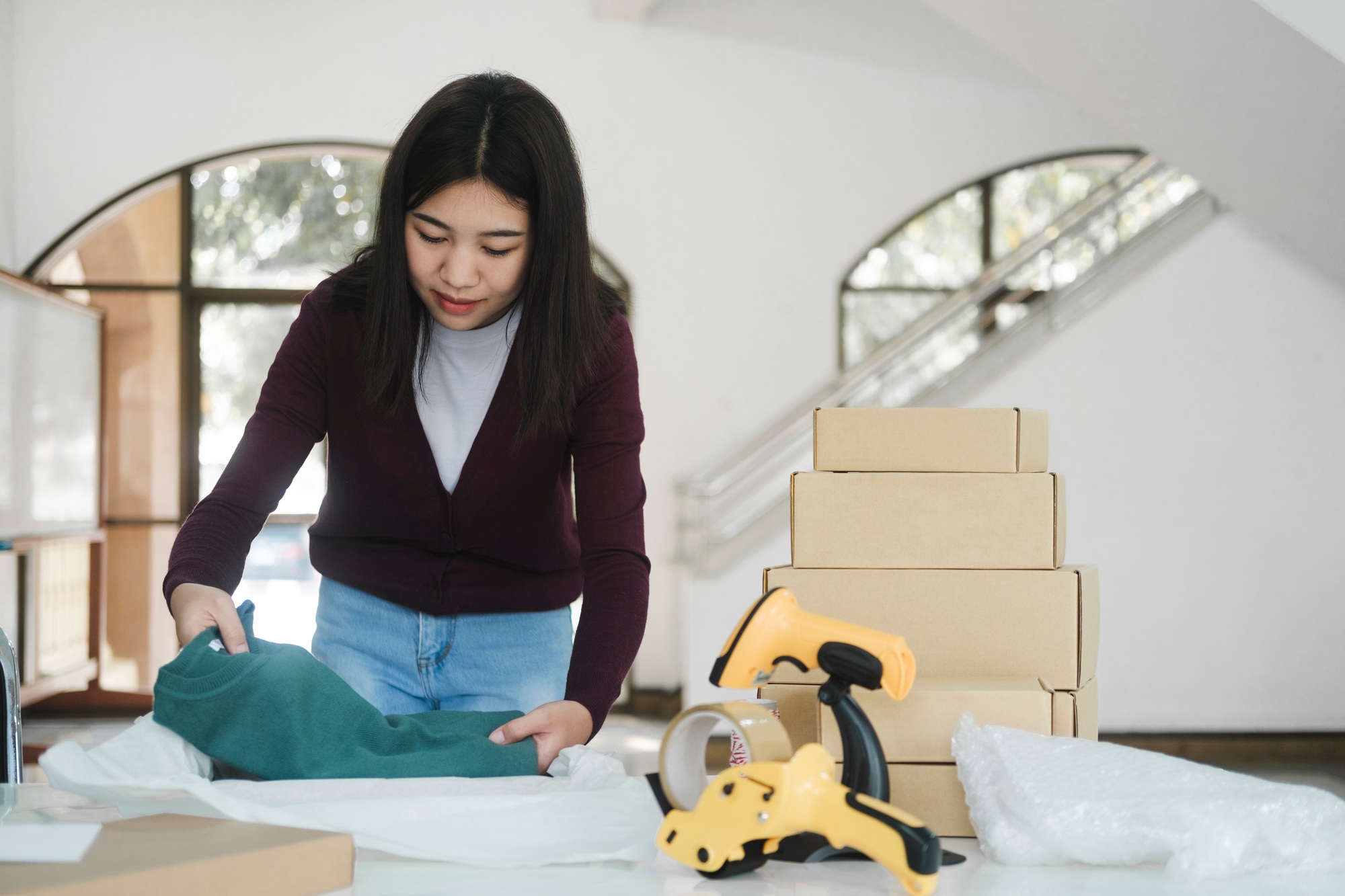 Businesswoman folding clothes for online order.