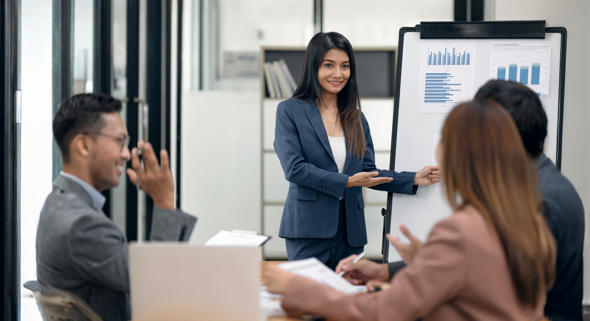 Businesswoman presenting market research results to focused diverse colleagues in office.