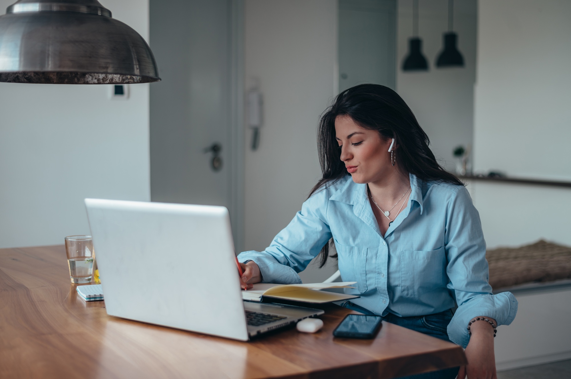 Businesswoman using a laptop and a business planner in a home office