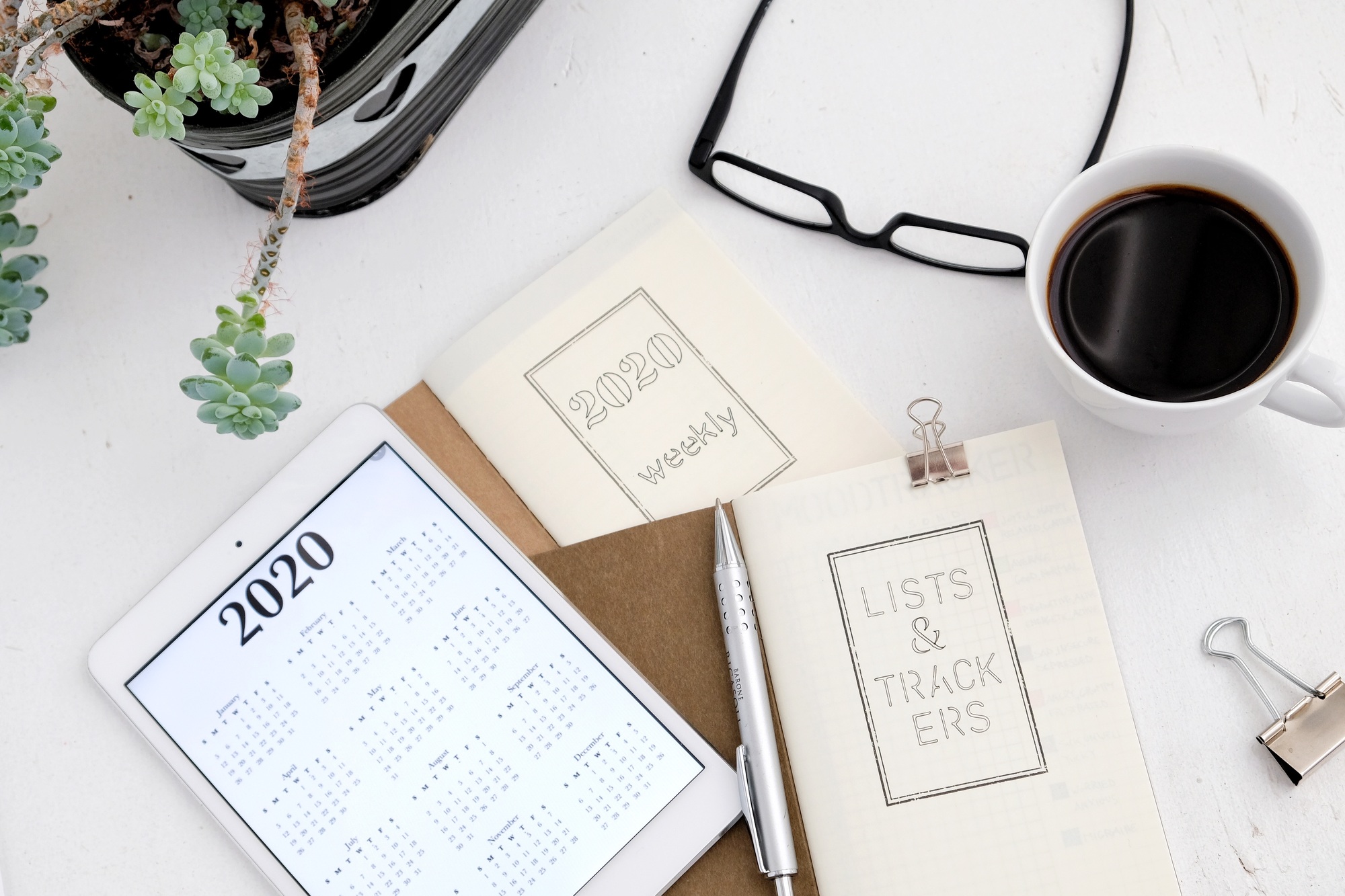 Calendar, cup of coffee, glasses and plant flat lay