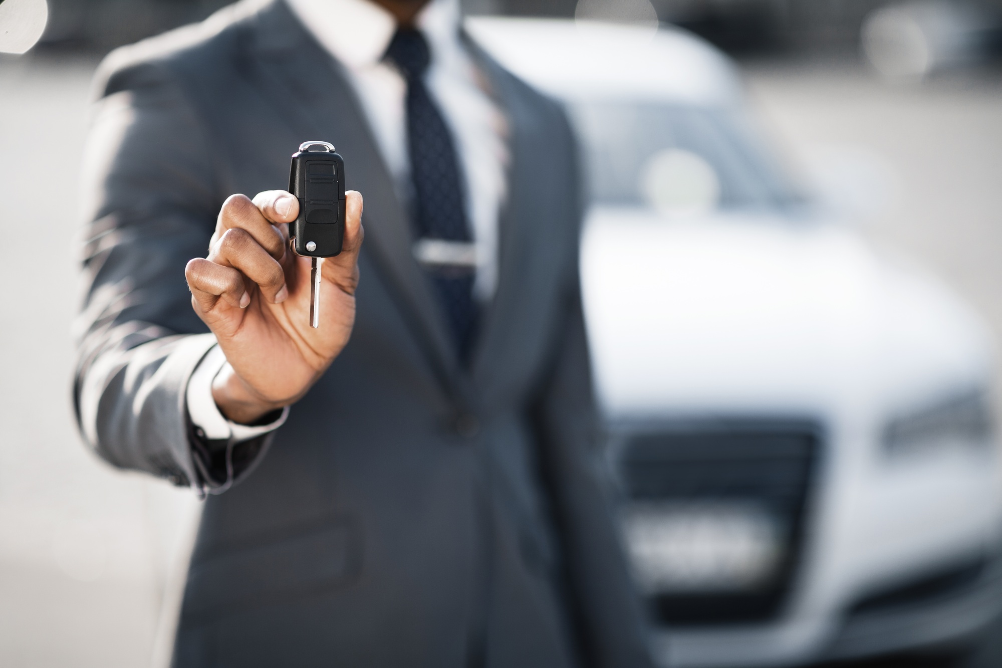 Car sale and rental concept. Businessman showing car key