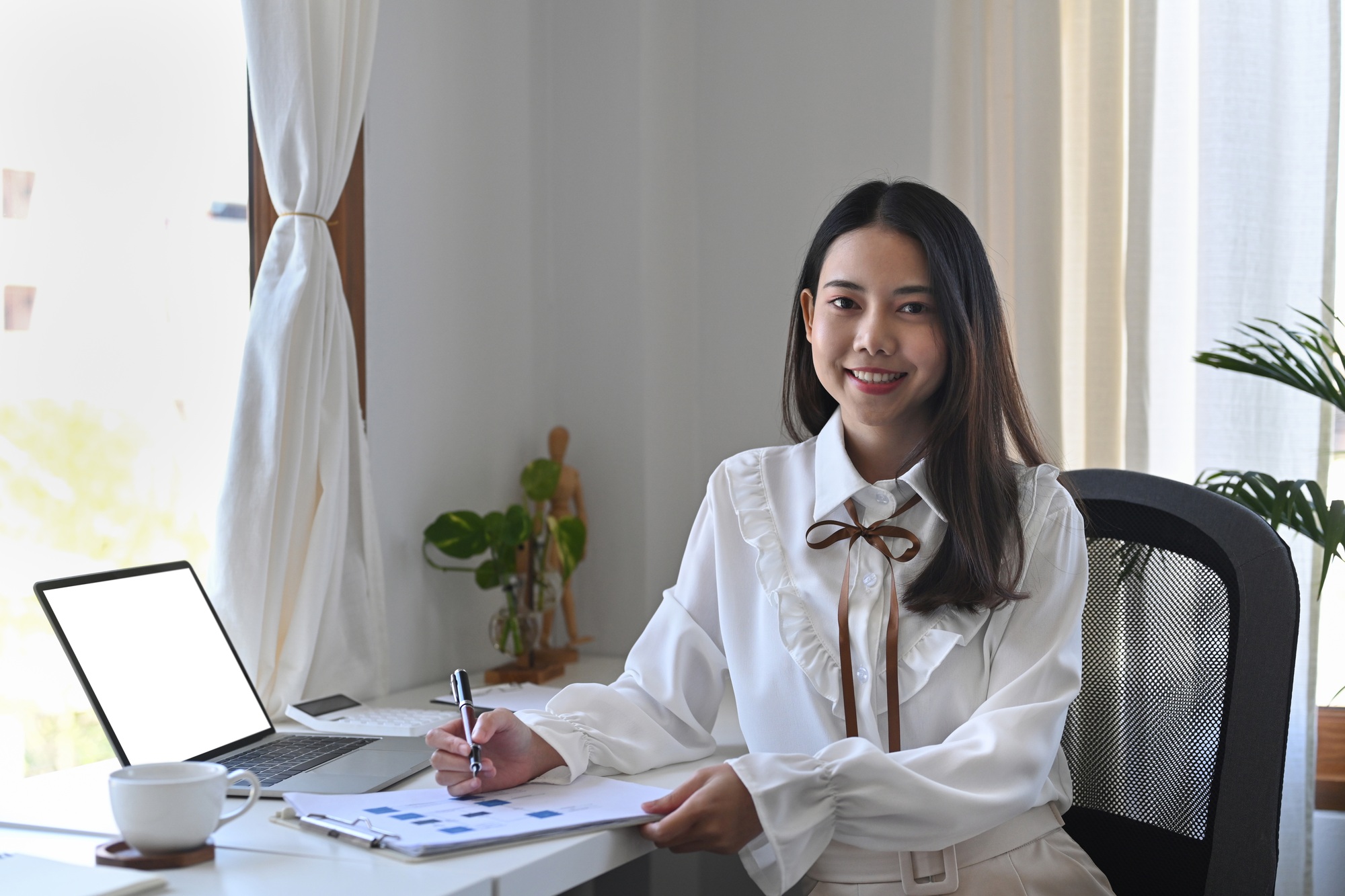 Cheerful businesswoman sitting in office ad smiling at camera.