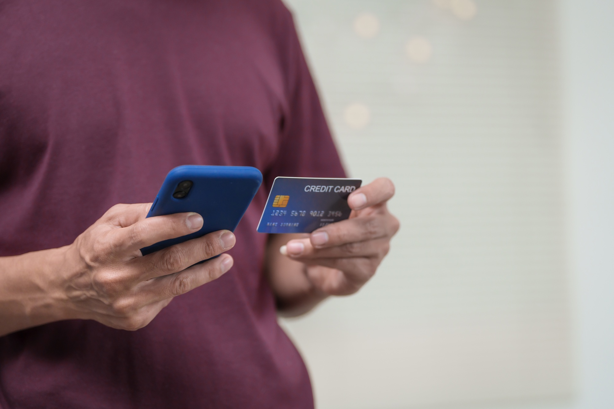 Close-up of a man's hand holding a bank credit card, highlighting online services lending access