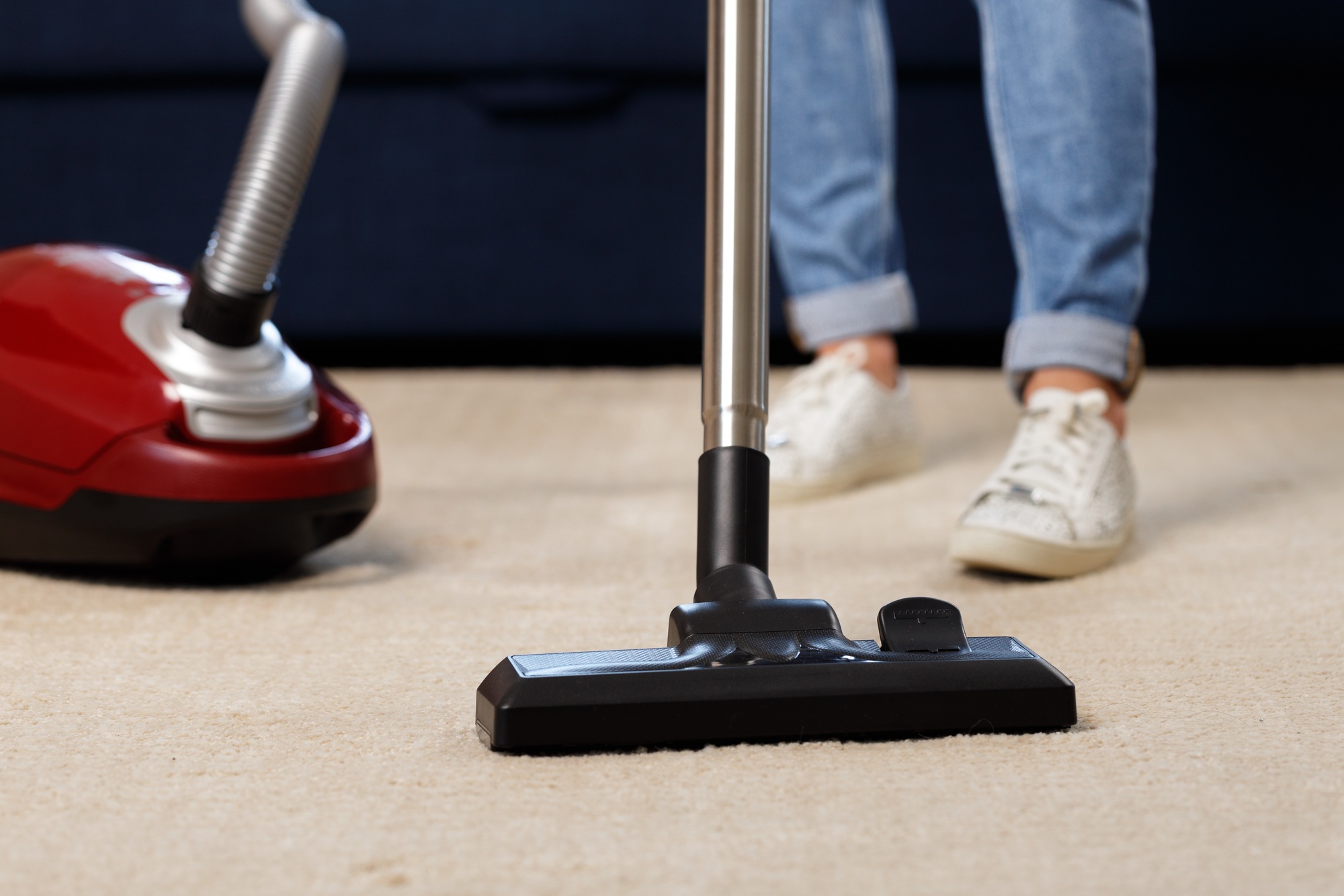 Close up of a woman vacuum-cleaning the carpet