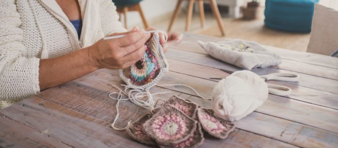 Close up of female people doing crochet knitting work alone at home for hobby or work.