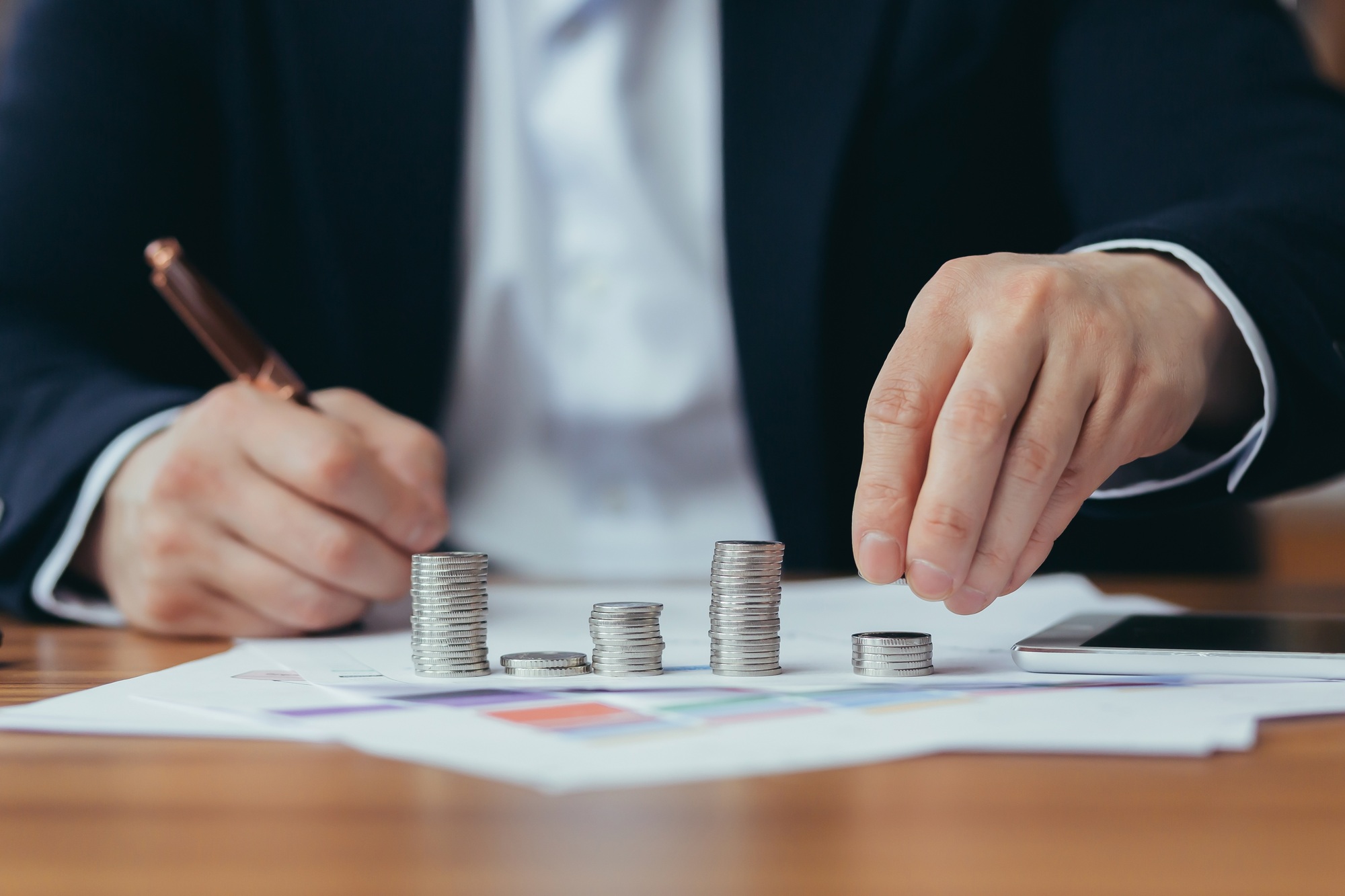 Close up photo, hands of a banker businessman counting coin money, and making calculations