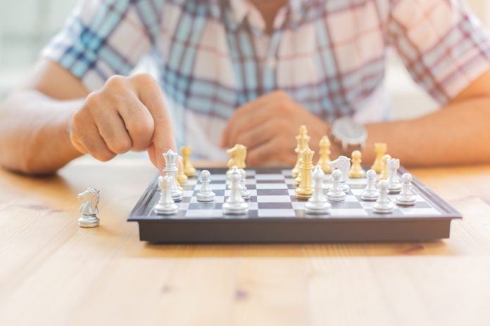 Closeup image of a leader moving and playing chessboard game.