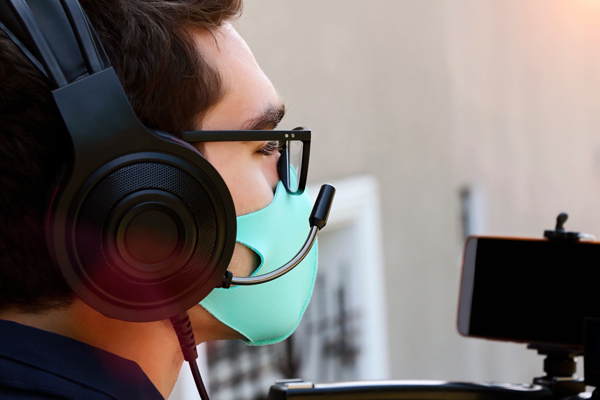 Closeup photography of videographer working outdoor.Face mask as protection from covid on the face.