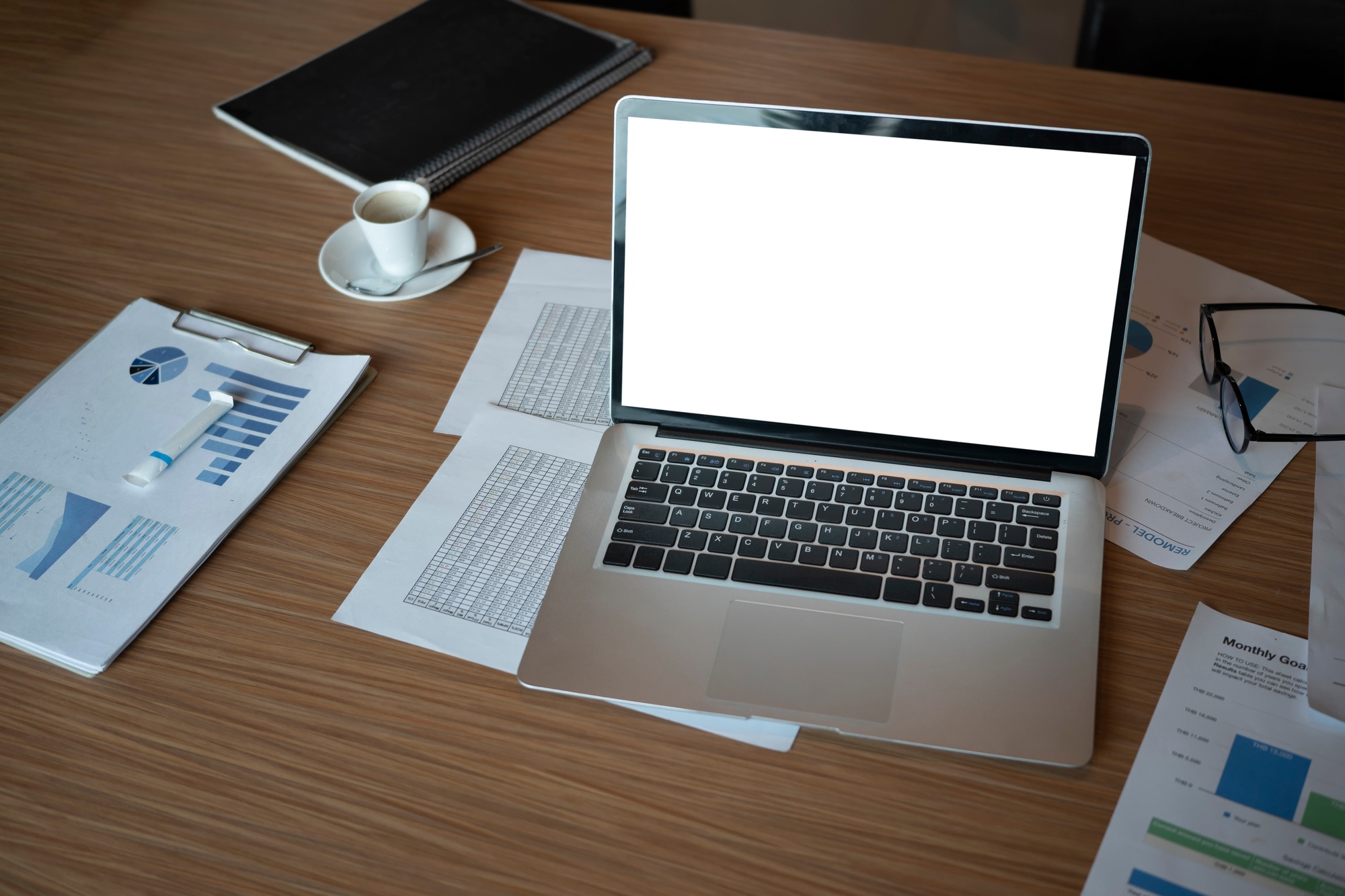 Computer laptop and financial documents on wooden table.