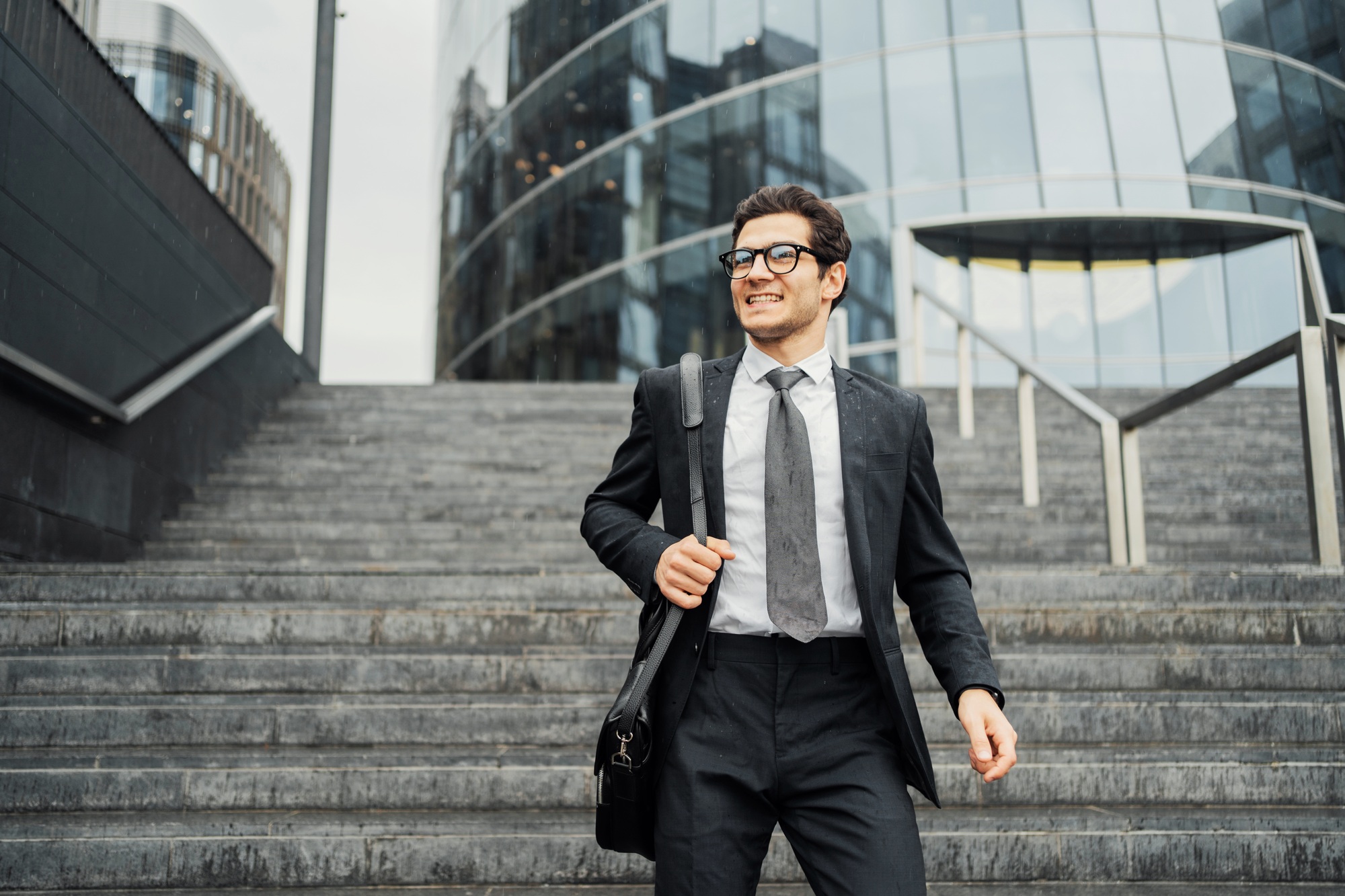 Confident businessman walking downstairs outside modern office building.