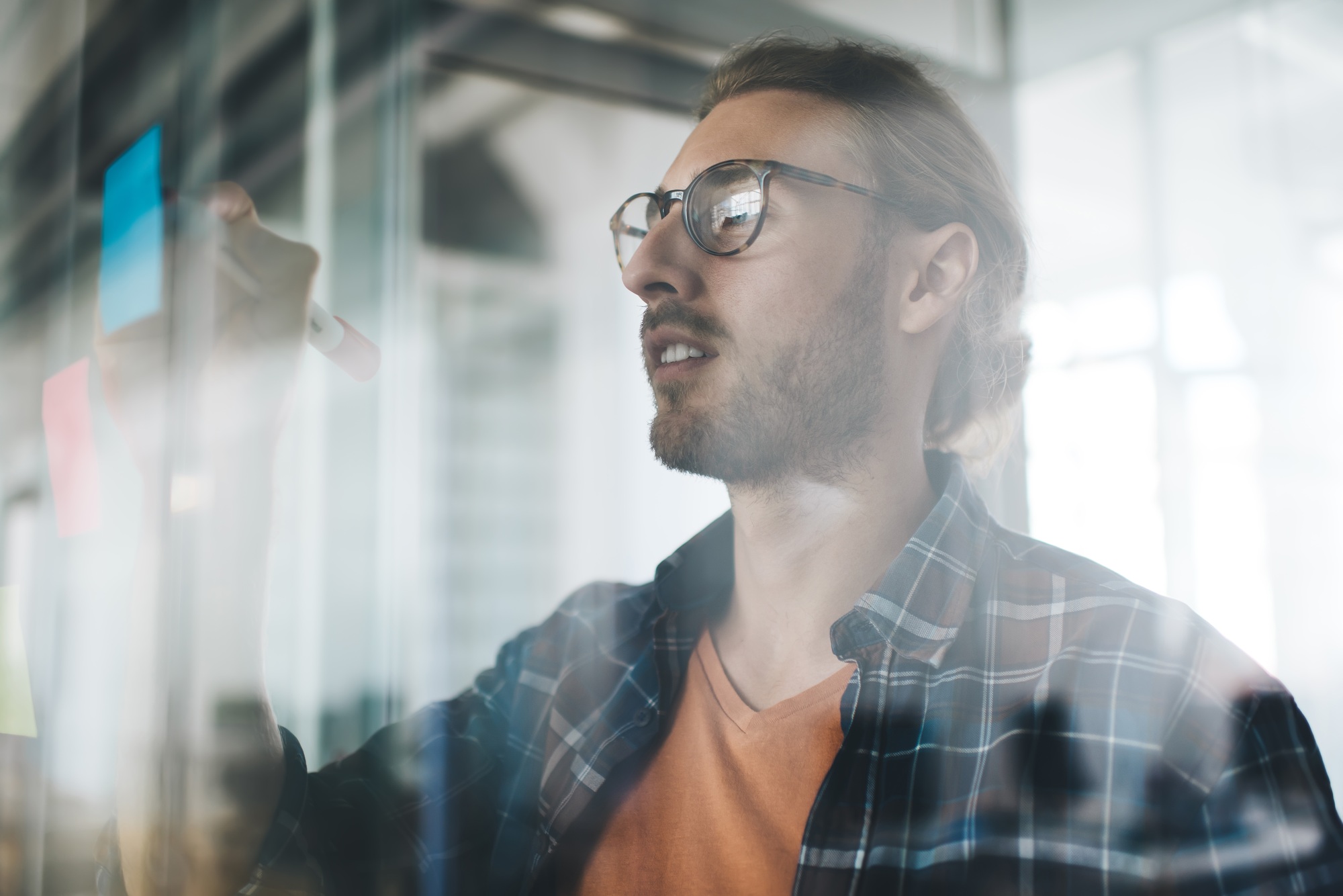 Confident male entrepreneur analyzing memo stickers working in office interior