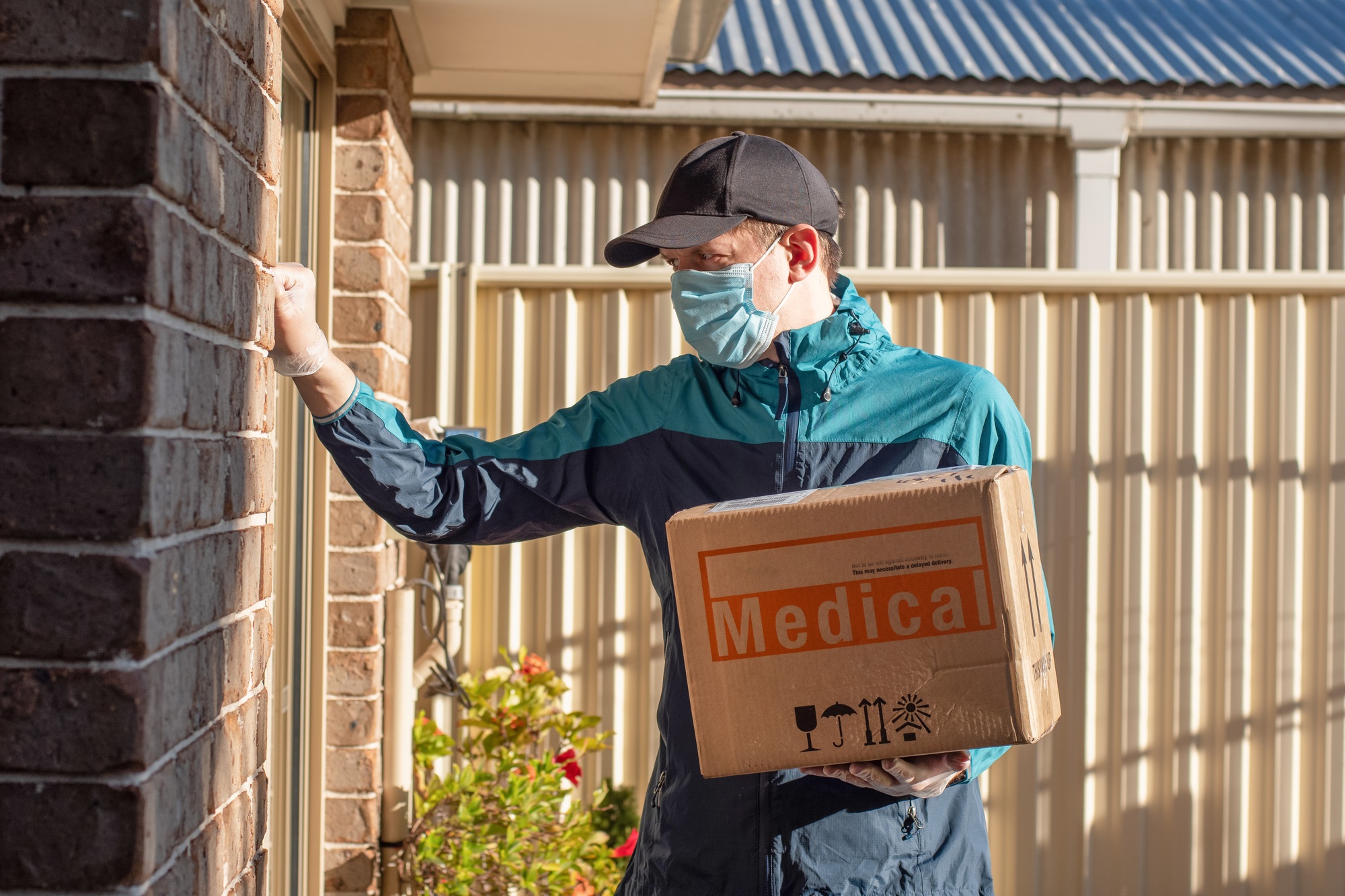 Contactless delivery during COVID-19concept. Courier wearing mask and gloves knocks on the door