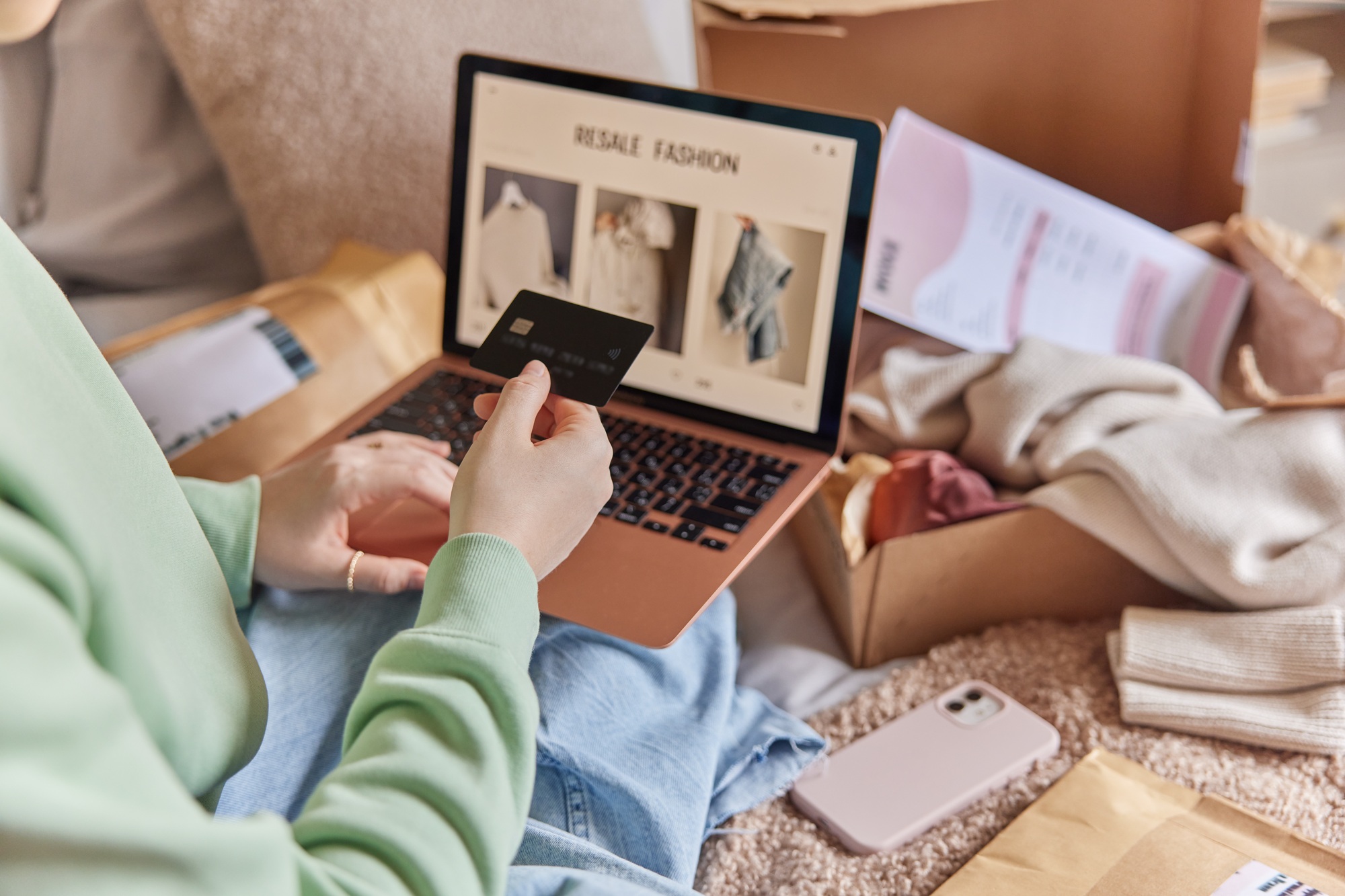 Cropped image of unrecognizable woman holds credit card and uses laptop computer makes shopping