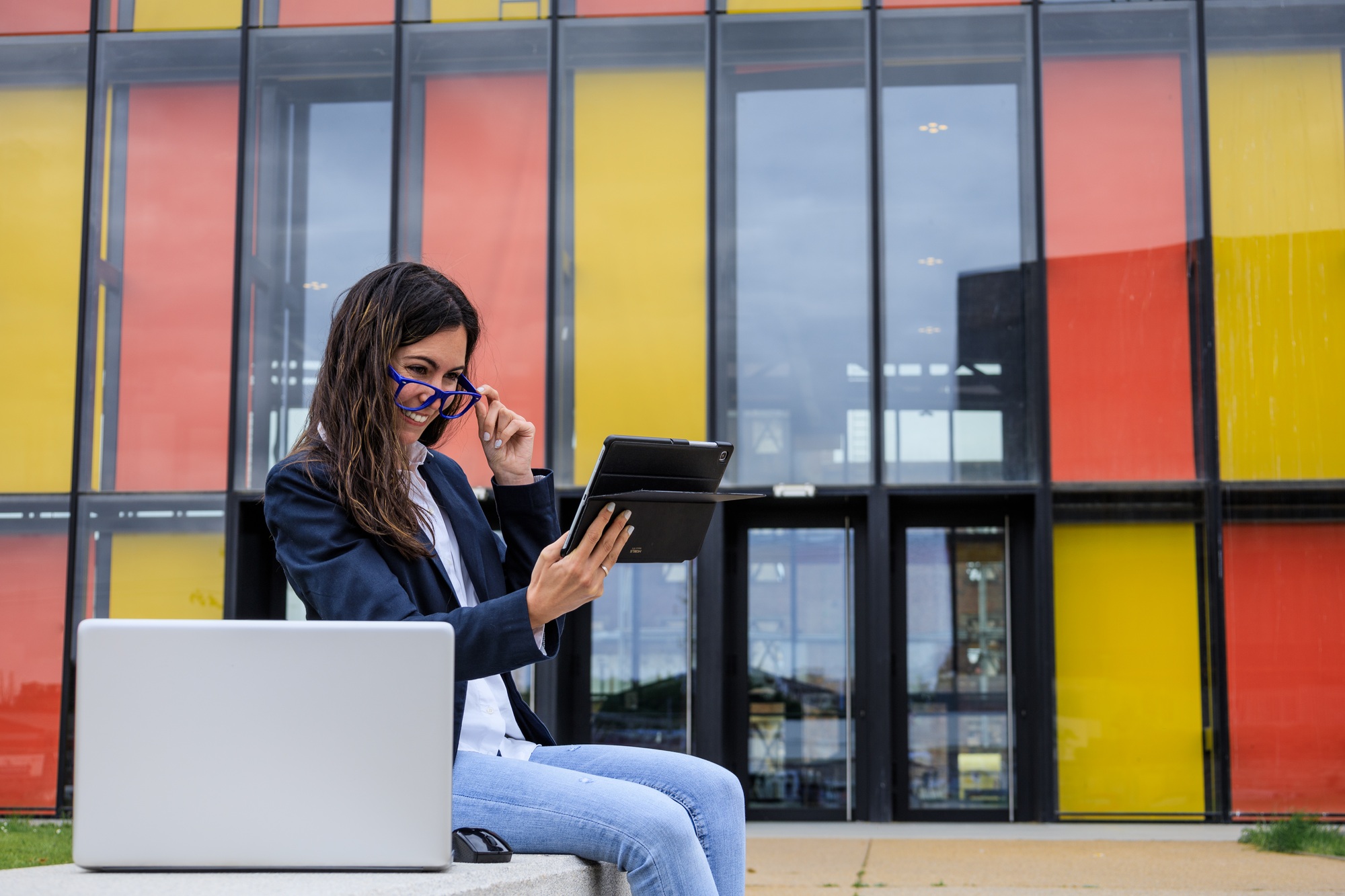 Entrepreneur working with multiple devices sitting in a bench in a trendy park