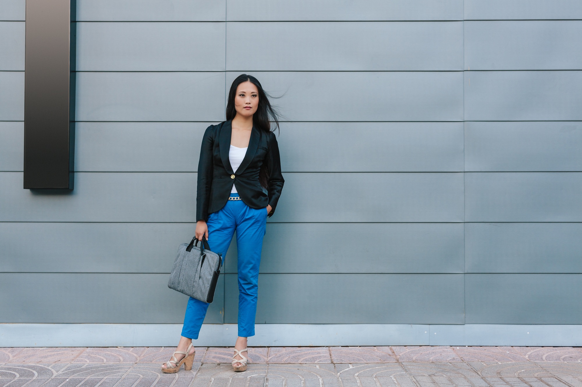 Ethnic businesswoman walking along street near building