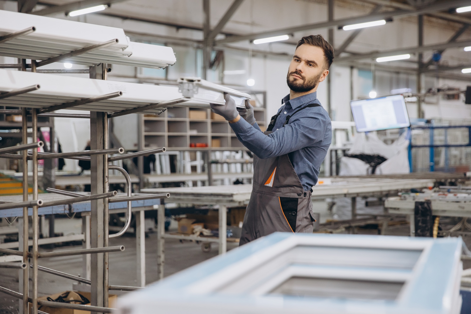 Factory worker storing aluminum window frames in warehouse