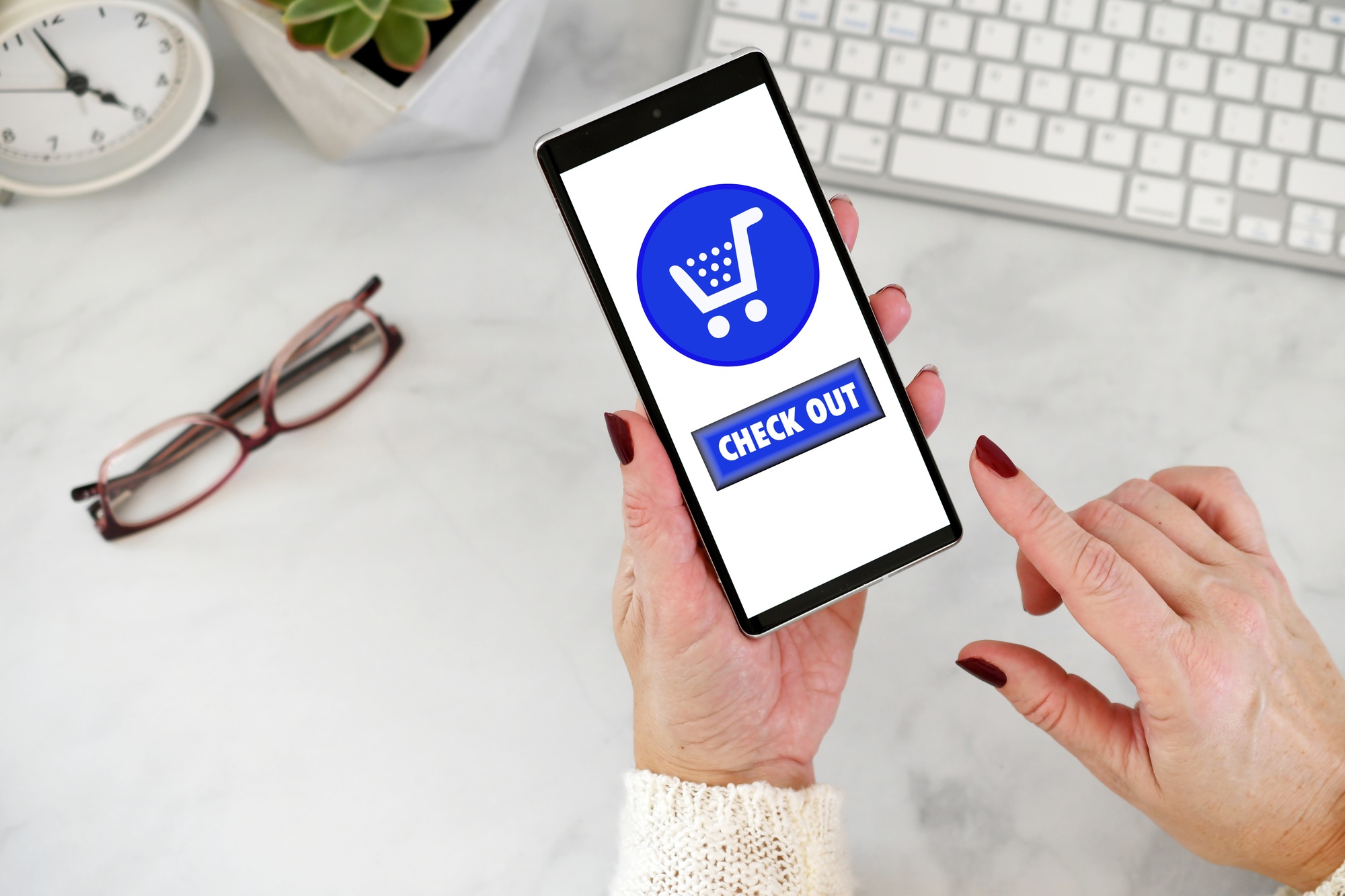 Female using cell phone to shop online - blue shopping cart with checkout check out button